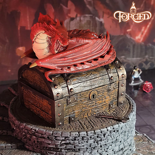 This is an environmental image of the Red colored Forged Gaming Wyvern Dice Chest sitting on a piece of gaming terrain.