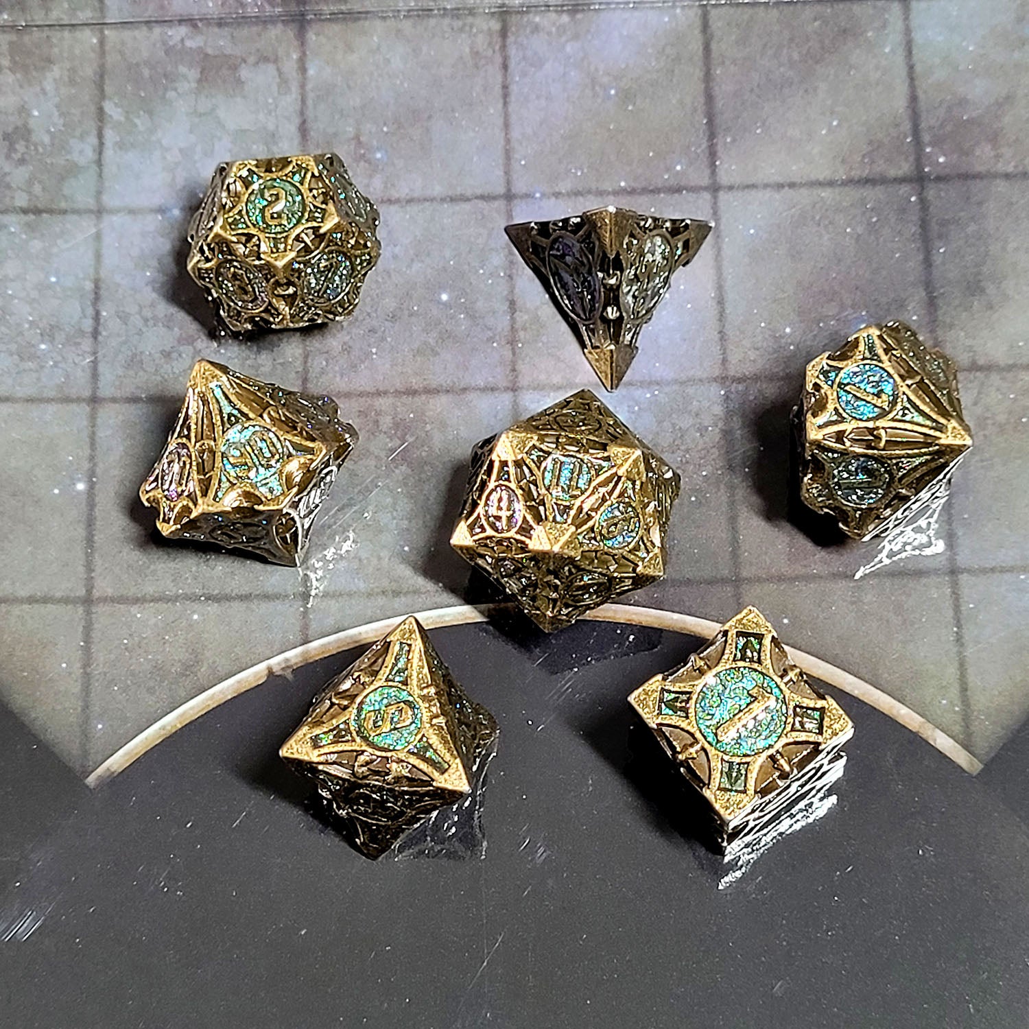 This is an environmental image of the Forged Gaming Arcane Enigma Metal RPG Dice Set. The photo was taken against the background of a gameboard.