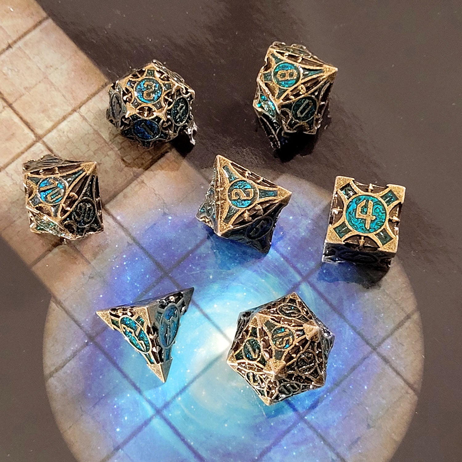 This is an environmental image of the Forged Gaming Arcane Enigma Gold Blue Metal RPG Dice Set. The photo was taken against the backdrop of a gameboard.