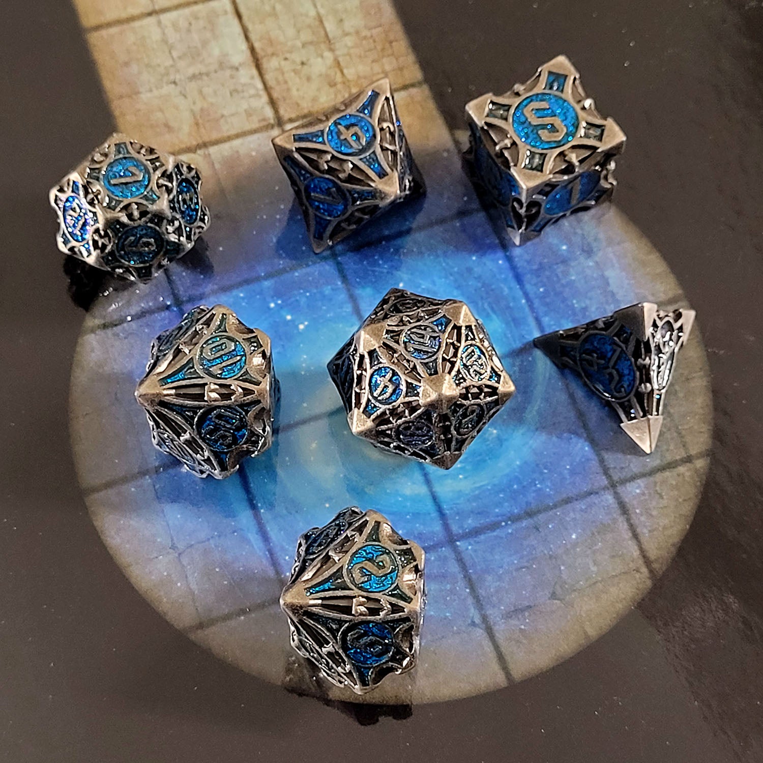 This is an environmental image of the Forged Gaming Arcane Enigma Iron Blue Metal RPG Dice Set. The photo was taken using a game board as a background.