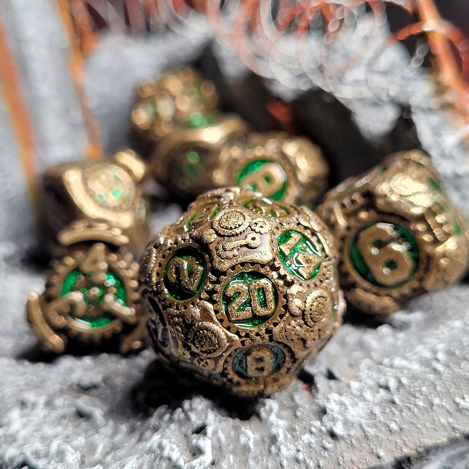 This is an environmental image of the Forged Gaming Chronomica Mechanium Gold Green Metal RPG Dice Set. This photo was taken using razor wire wargaming terrain as a background.