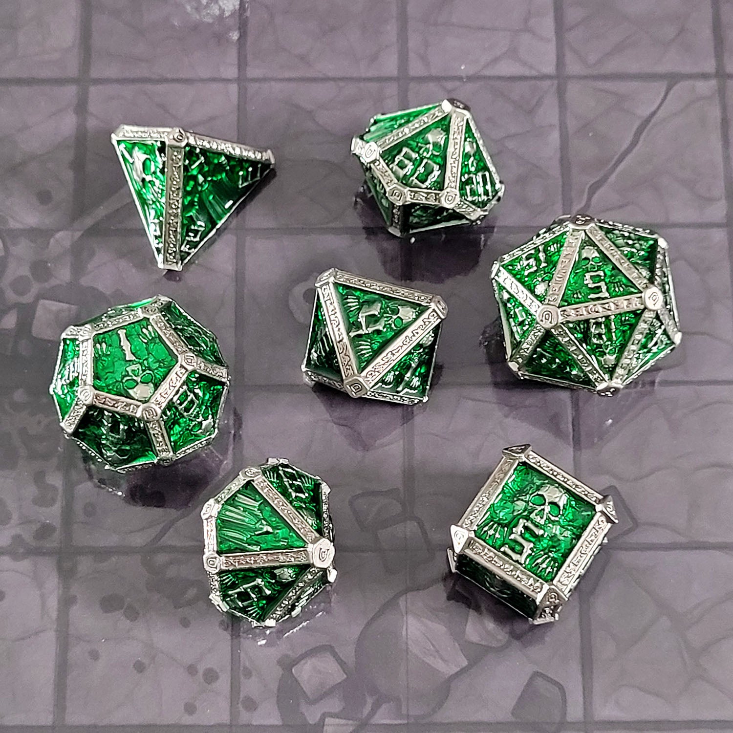 This is an environmental image of the Forged Gaming Cryptic Reliquary Silver Green Metal RPG Dice Set. The photo was taken against the backdrop of the Dungeon Floor Encounter Map.