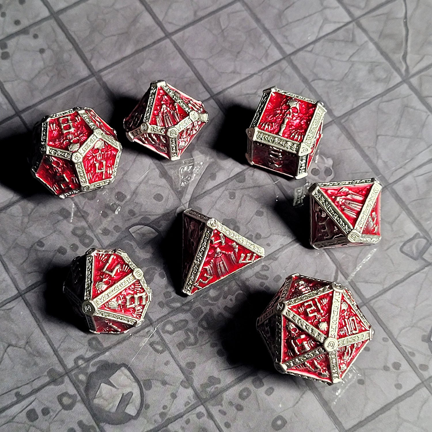 This is an environmental image of the Forged Gaming Cryptic Reliquary Silver Red Metal RPG Dice Set. The photo was taken against the backdrop of the Dungeon Floor Encounter Map.