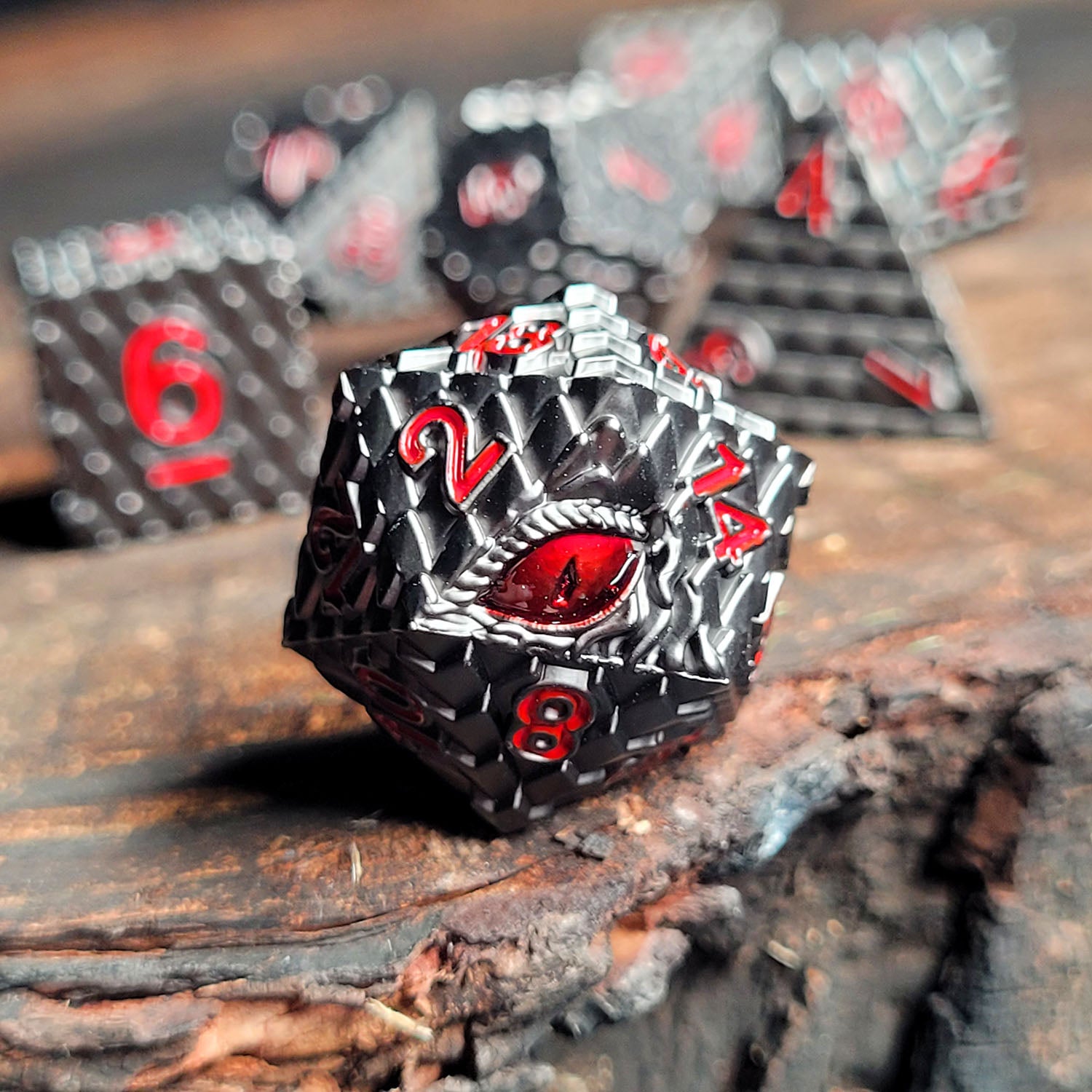 This is an environmental image of the Forged Gaming Dragon's Gaze Gunmetal Metal RPG Dice Set. The photo was taken using a piece of scorched wood as a backgound