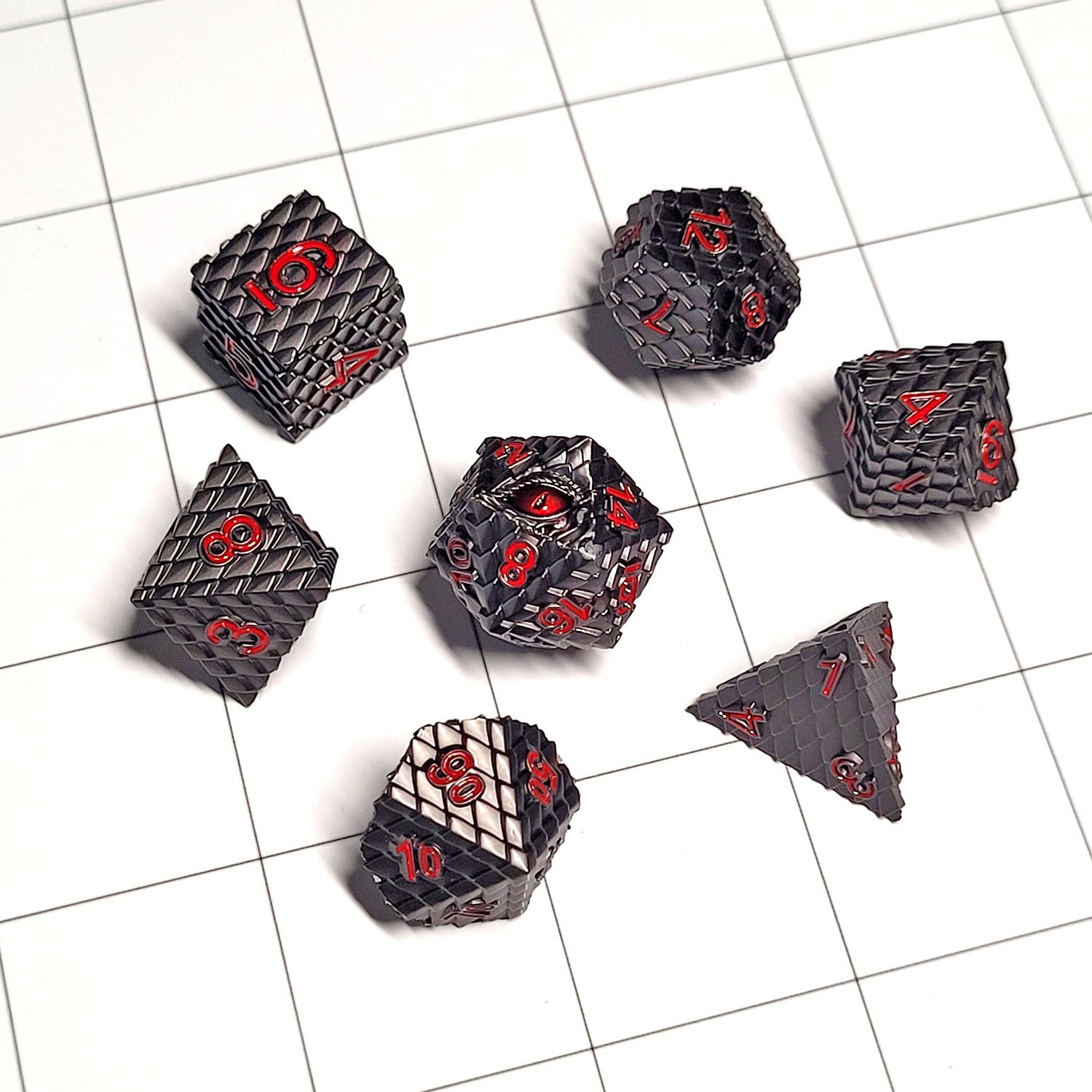 This is an environmental image of the Forged Gaming Dragon's Gaze Gunmetal Metal RPG Dice Set. The photo was taken using the White Grid Encounter Map as a background.