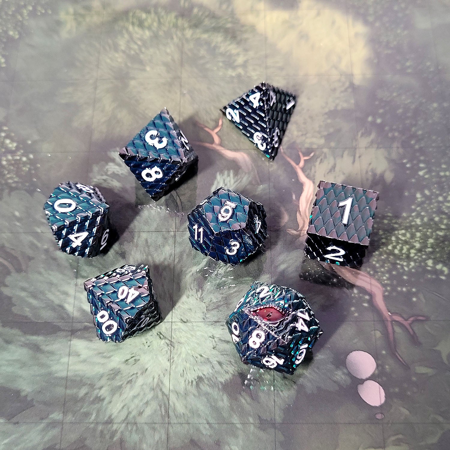 This is an environmental image of the Forged Gaming Dragon's Gaze Silver Blood Metal RPG Dice Set featuring red dragon eye on the D20 face. The photo was taken using the Wooded Forest Encounter Map as a background.