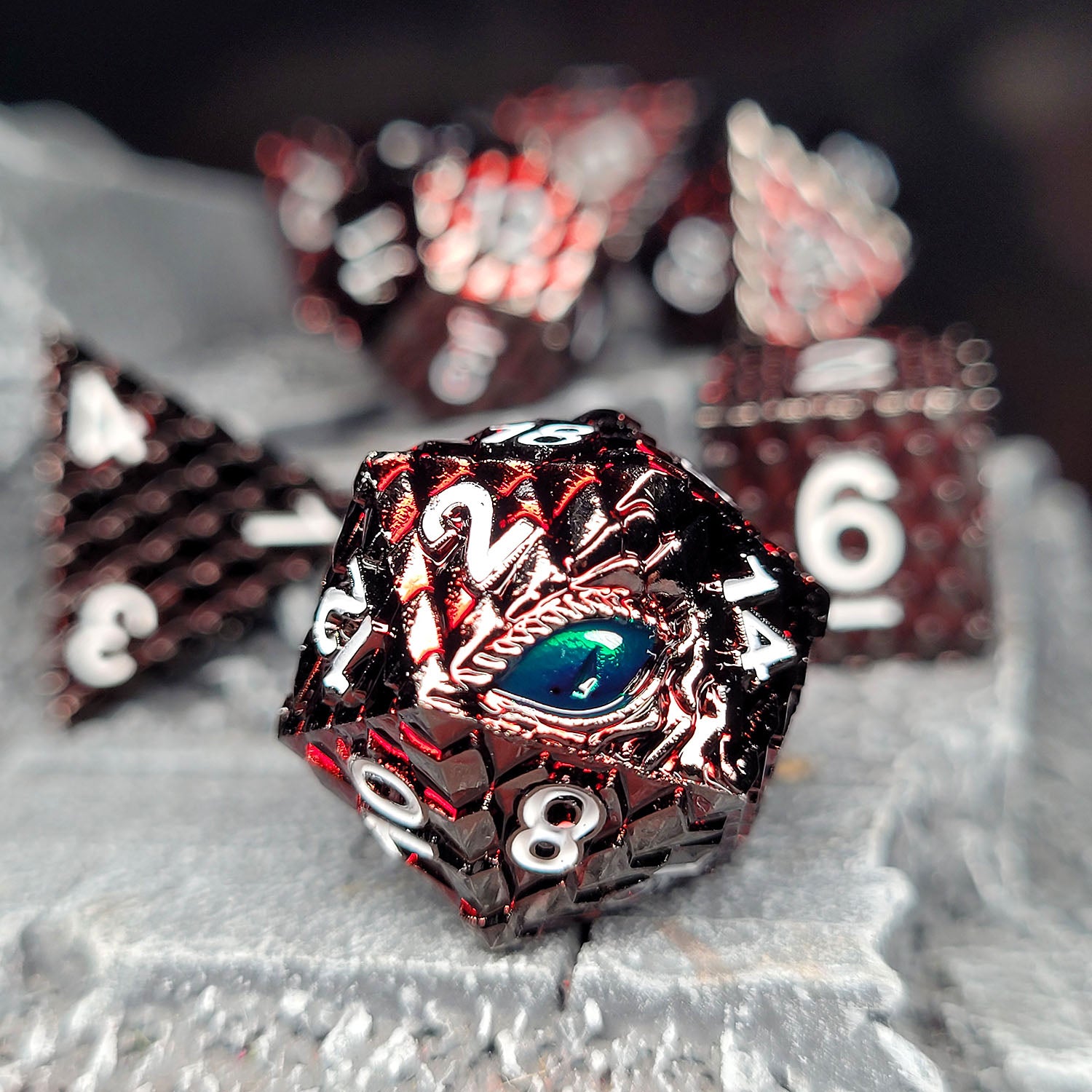 This is an environmental image of the Forged Gaming Dragon's Gaze Red metal RPG dice set. The photo was taken using a piece of stone wargaming terrain as a background.