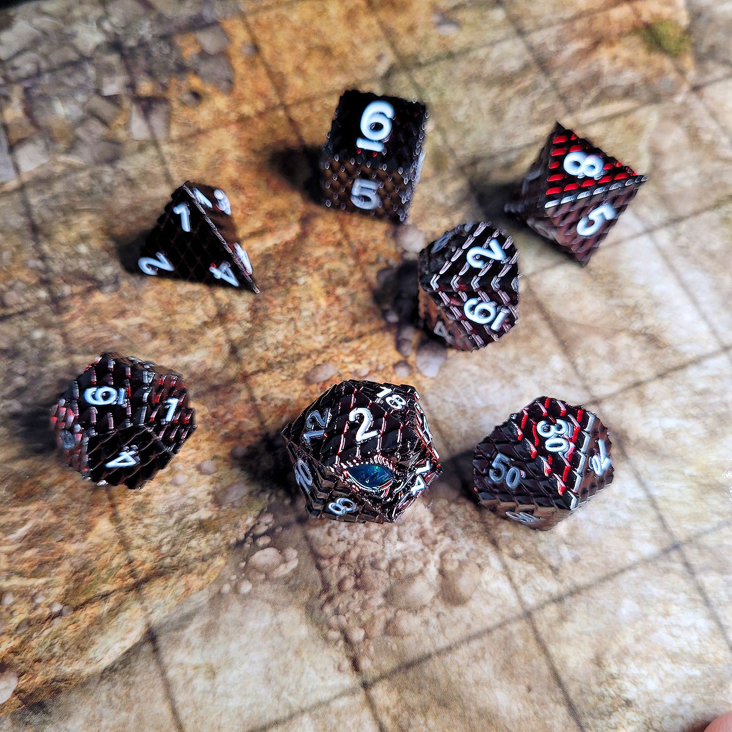 This is an environmental image of the Forged Gaming Dragon's Gaze Red metal RPG dice set. The photo was taken using an encounter map game board as a background.