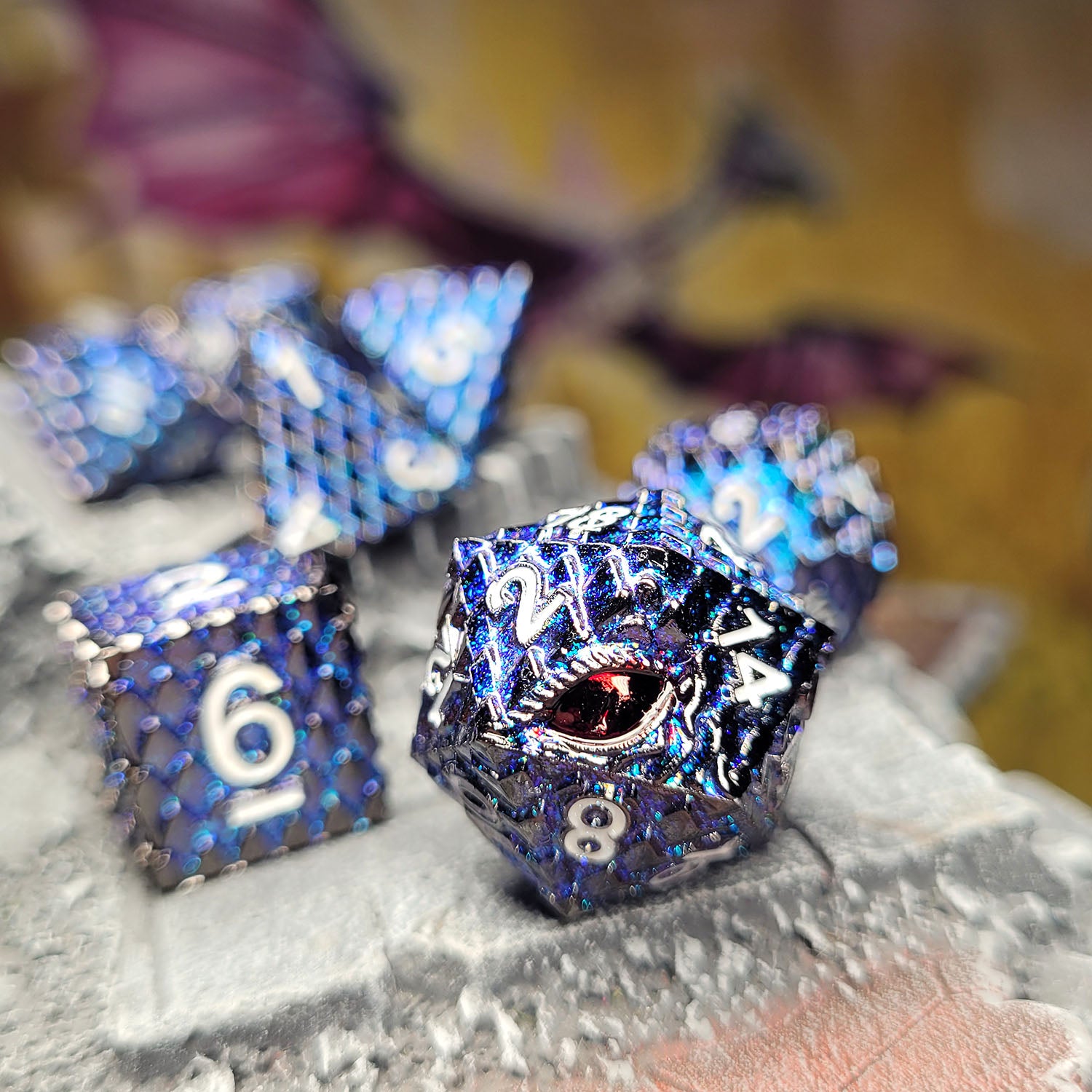 This is an environmental image of the Forged Gaming Dragon's Gaze Shimmering Blue metal RPG dice set. The photo was taken using a piece wargaming terrain as a background.