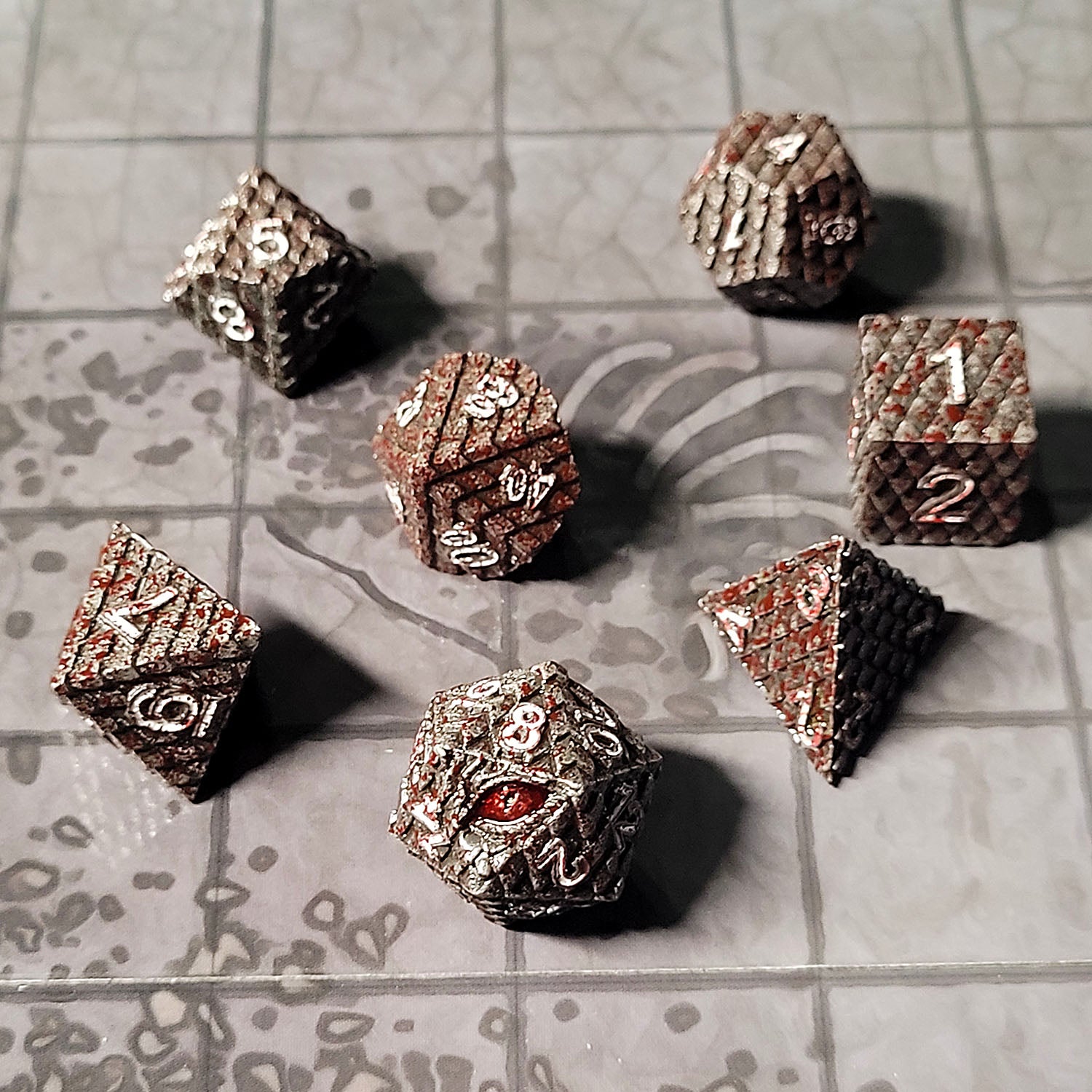 This is an environmental image of Forged Gaming Dragon's Gaze Silver Blood Metal RPG Dice Set photographed using the Dungeon Floor Encounter Map as a background.