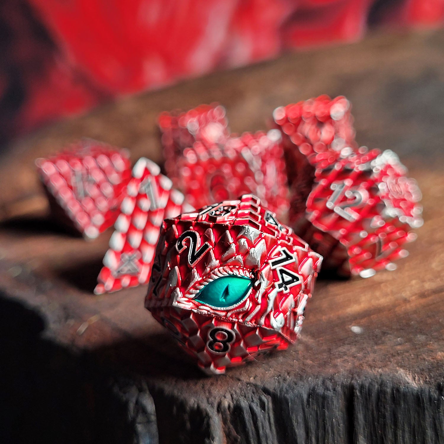 This is an environmental image of the Forged Gaming Dragon's Gaze Silver Red Metal RPG Dice Set. The photo was taken using a burned wood platform as a background.