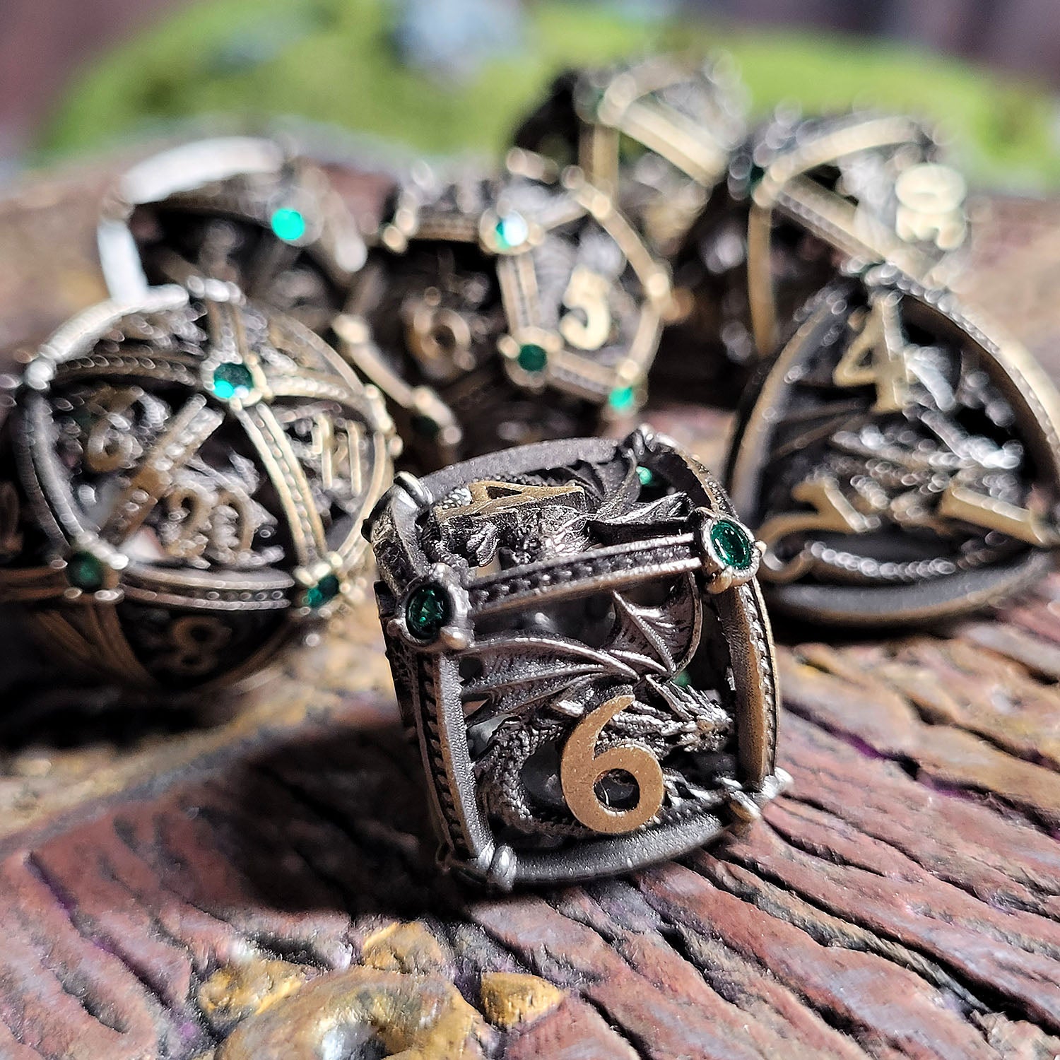 This is an environmental image of the Forged Gaming Dragon's Jewel Ancient Gold Hollow Metal RPG Dice Set. The photo was taken using a piece of wargaming terrain as a background.