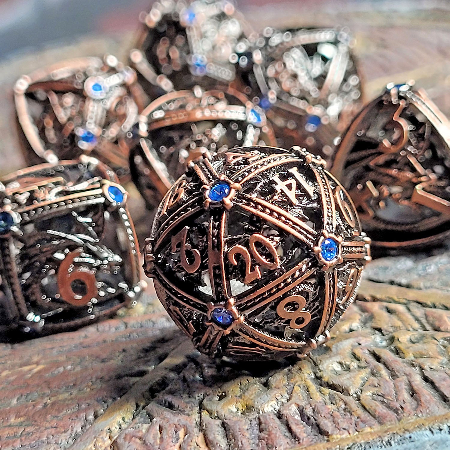 This is an environmental image of the Forged Gaming Dragon's Jewel Copper Hollow Metal RPG Dice Set. The photo was taken using a piece of wargaming terrain as a background.