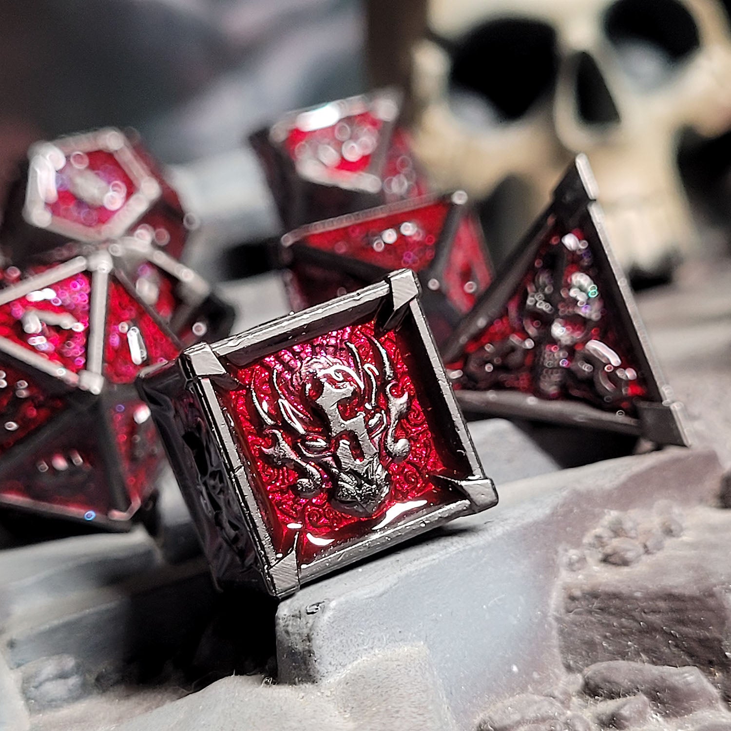 This is an environmental image of the Forged Gaming Ossuary Obscura Gunmetal Red Metal RPG Dice Set. The image was taken using a piece of temple wargaming terrain as a background.