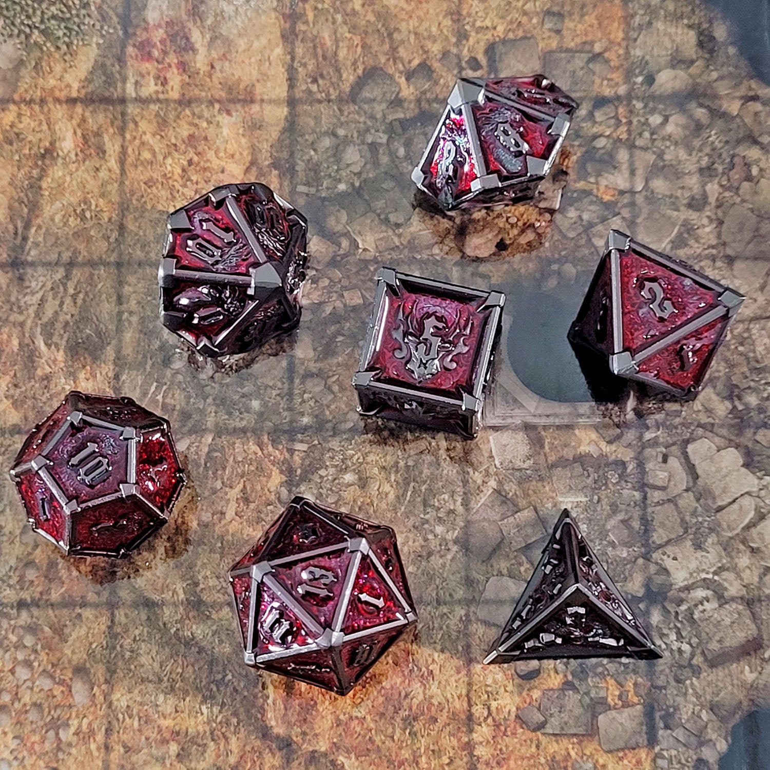 This is an environmental image of the Forged Gaming Ossuary Obscura Gunmetal Red Metal RPG Dice Set. The photo was taken using the Mountain Pass Encounter Map as a background.