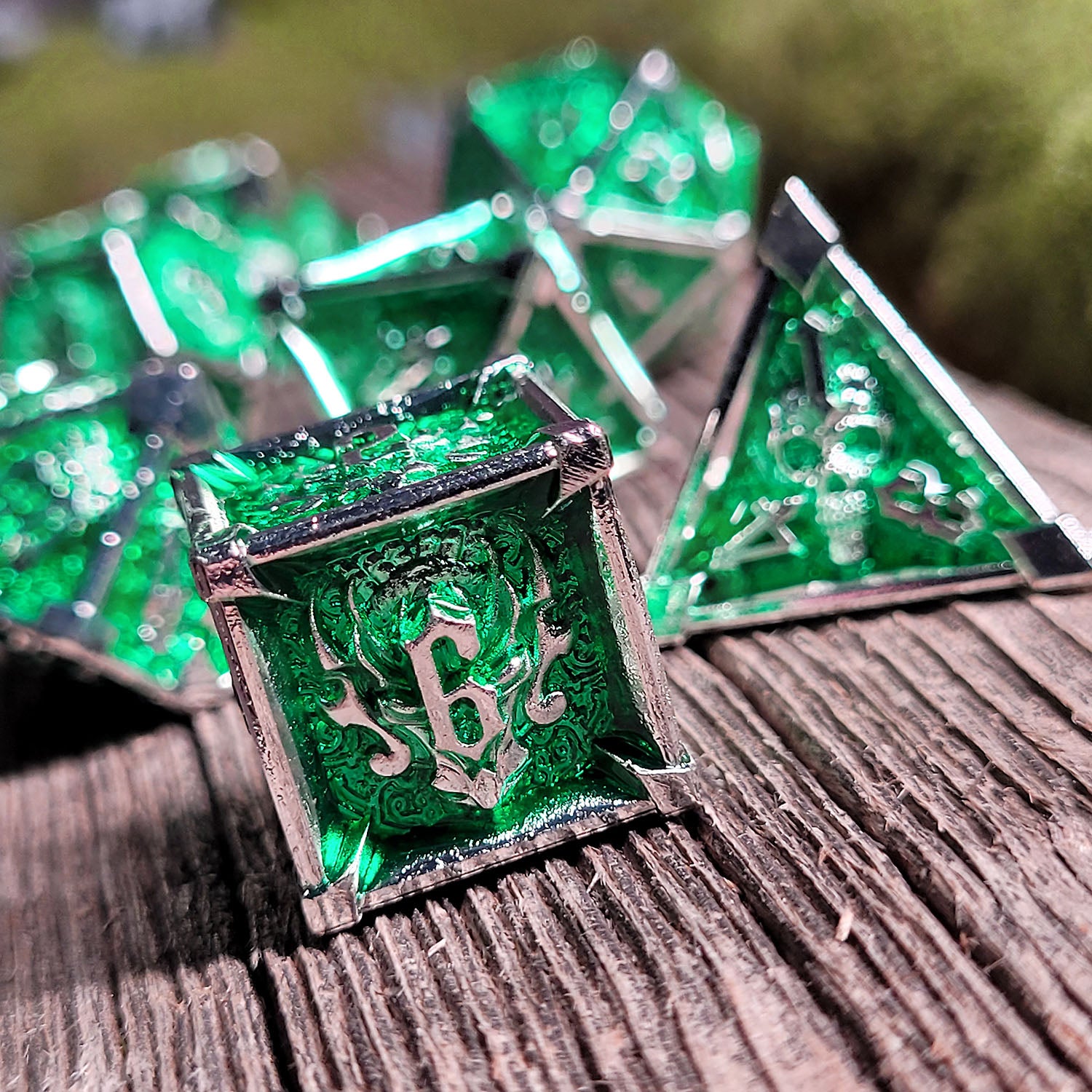 This is an environmental image of the Forged Gaming Ossuary Obscura Silver Green Metal RPG Dice Set. The photo was taken using a piece of wargaming terrain as a background.