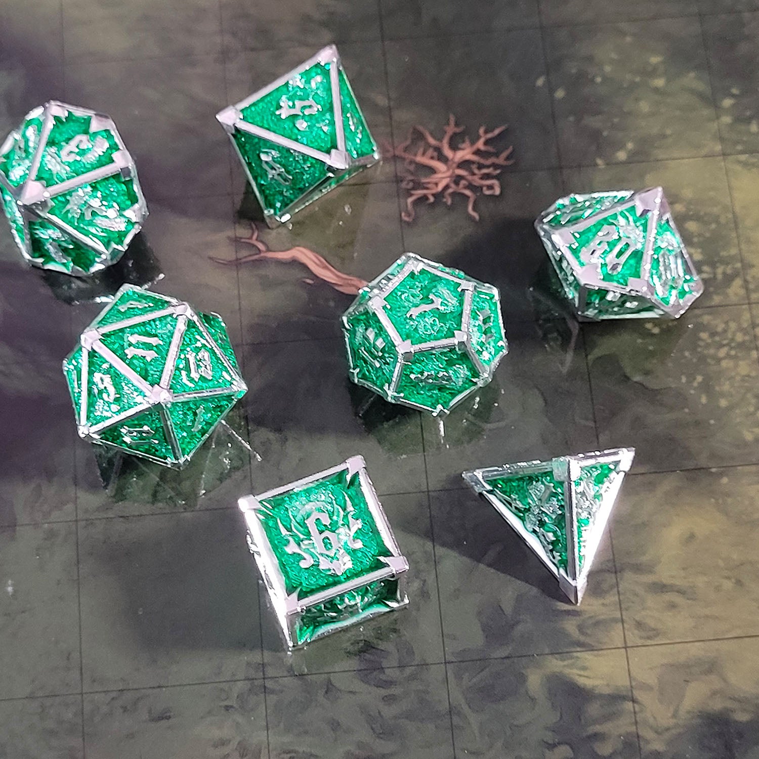 This is an environmental image of the Forged Gaming Ossuary Obscura Silver Green Metal RPG Dice Set. The photo was taken using the Wooded Forest Encounter Map as a background.