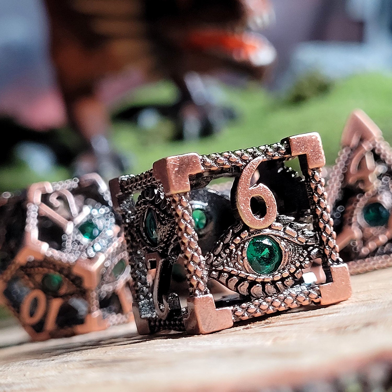 This is an environmental image of the Forged Gaming Serpent's Eye Copper Hollow Metal RPG Dice Set. This photo was taken using a piece of scorched wood as a background.