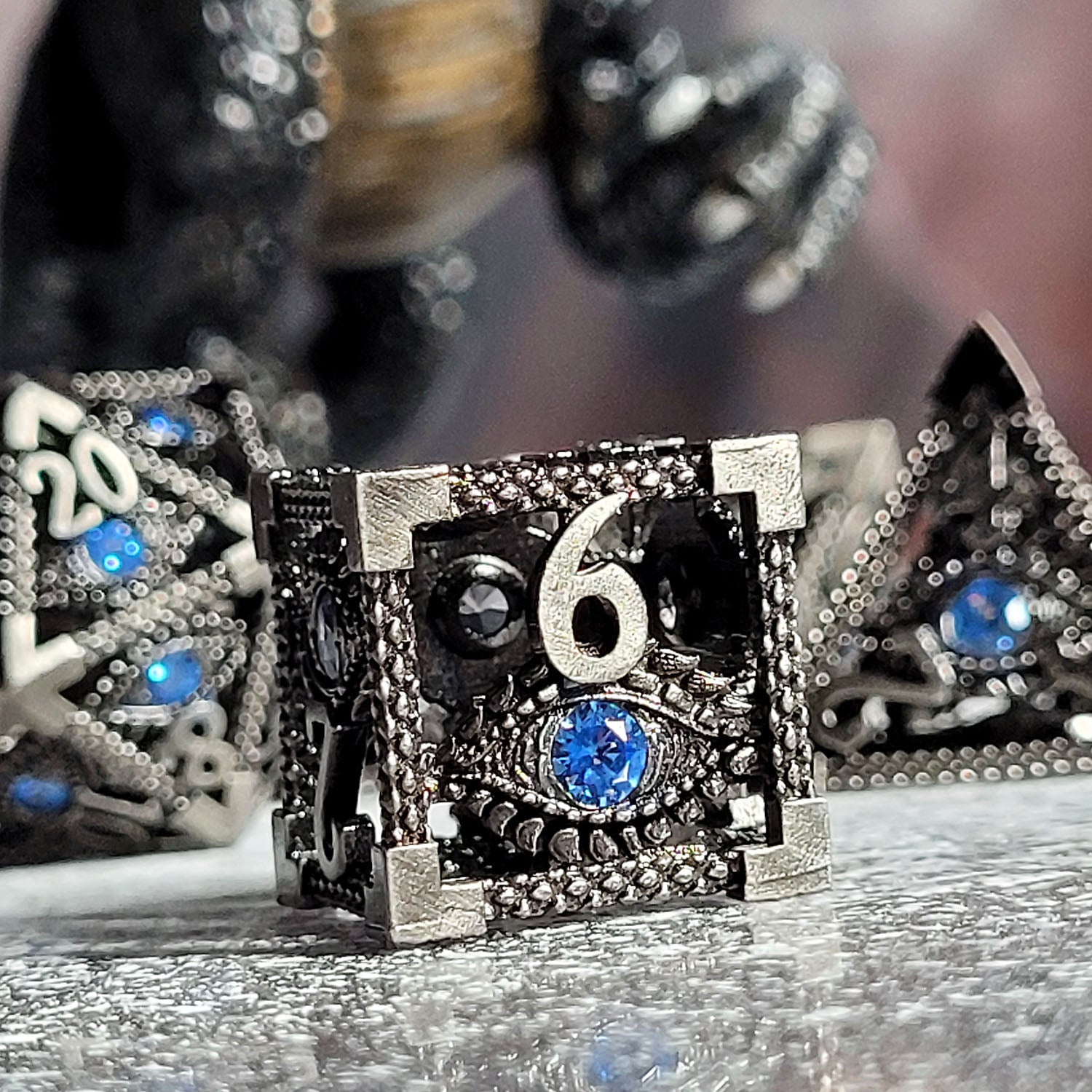 This is an environmental image of the Forged Gaming Serpent's Eye Silver Hollow Metal RPG Dice Set. The photo was taken using a bright reflective background.