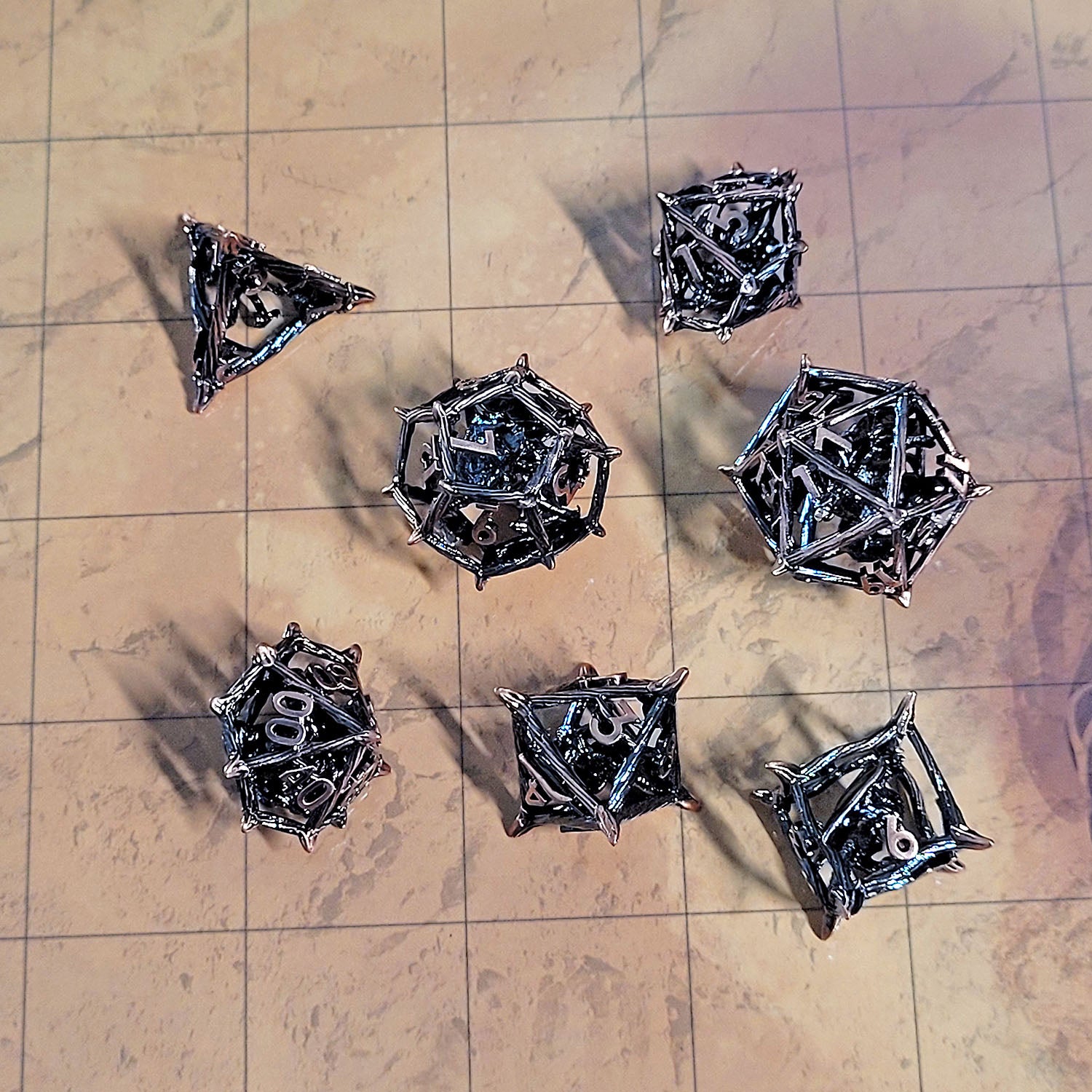 This in an environmental image of the Forged Gaming Wicker Dragon Copper Hollow Metal RPG Dice Set. The photo was taken using the Desert Sands Encounter Map as a background.