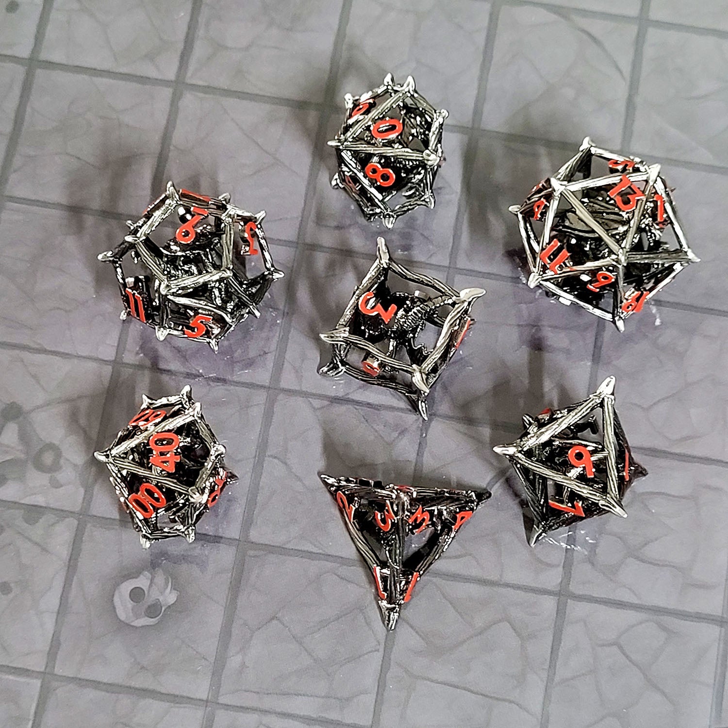 This is an environmental image of the Forged Gaming Wicker Dragon Silver Hollow Metal RPG Dice Set. The photo was taken using the Dungeon Floor Encounter Map as a background.