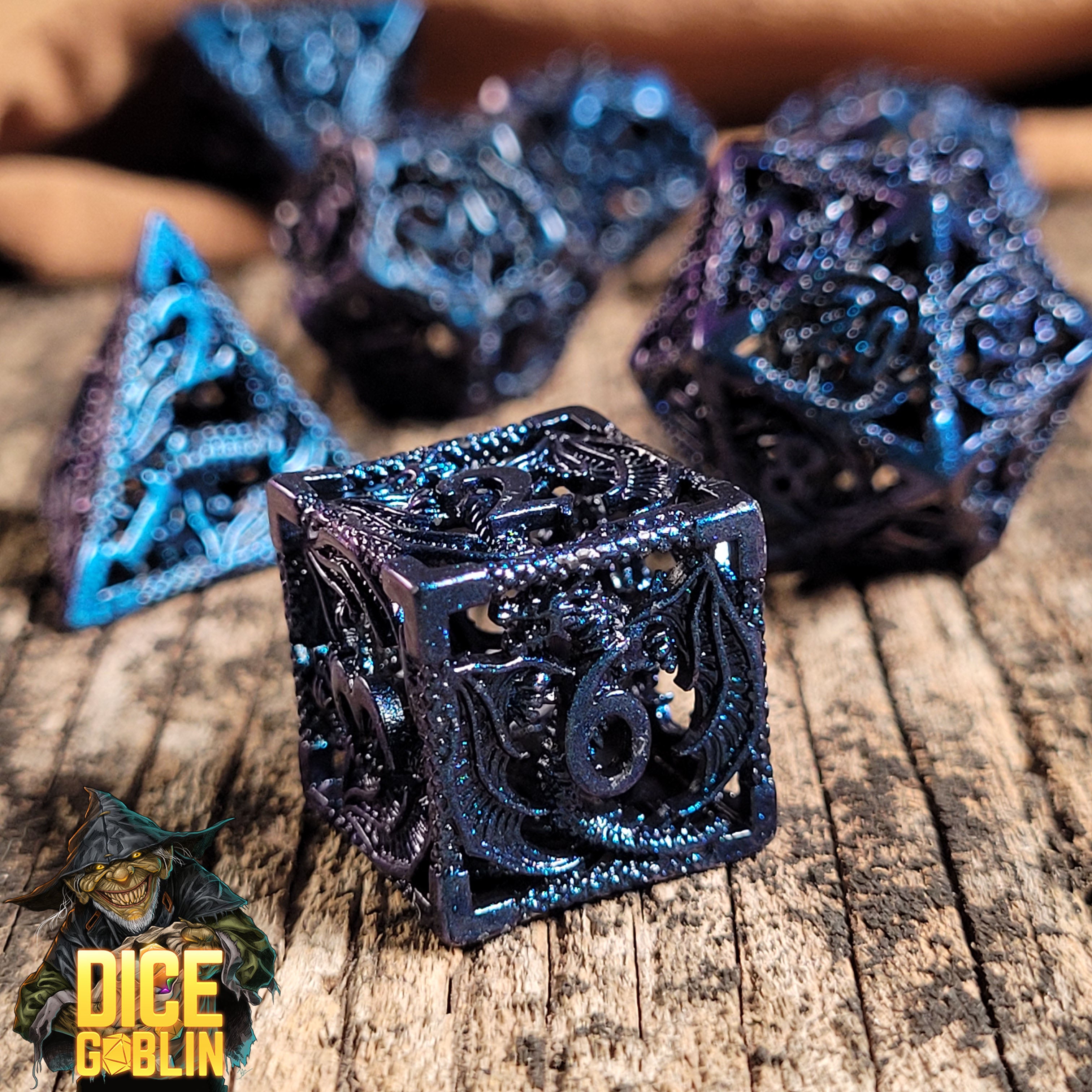 This is an environmental image of the Dice Goblin Dragon Rampant Metallic Blue Wash Hollow Metal RPG Dice Set taken on a distressed wood surface.