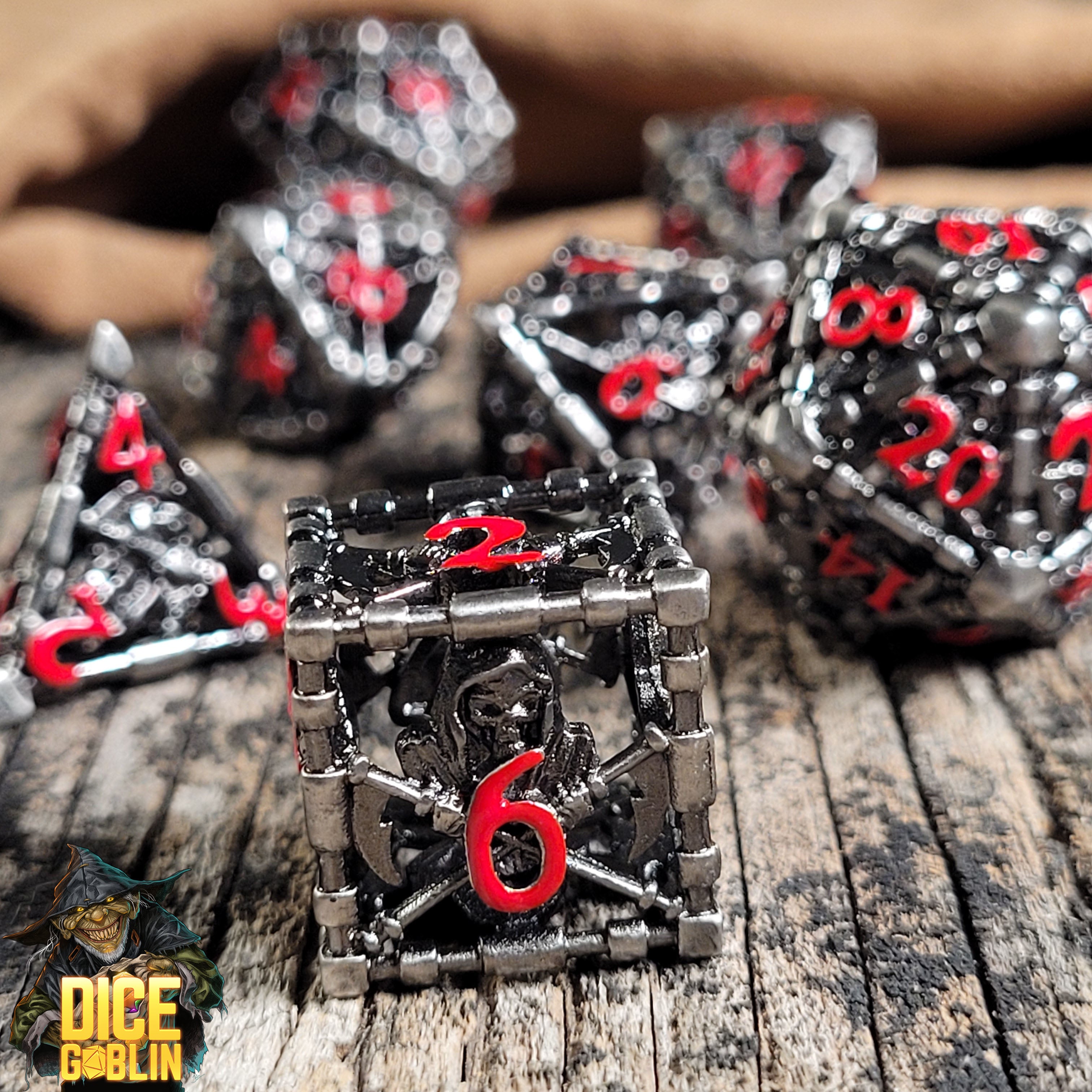 This is an environmental image of the Dice Goblin Reaper's Confine Silver with Red Hollow Metal RPG Dice Set on a distressed wood surface.
