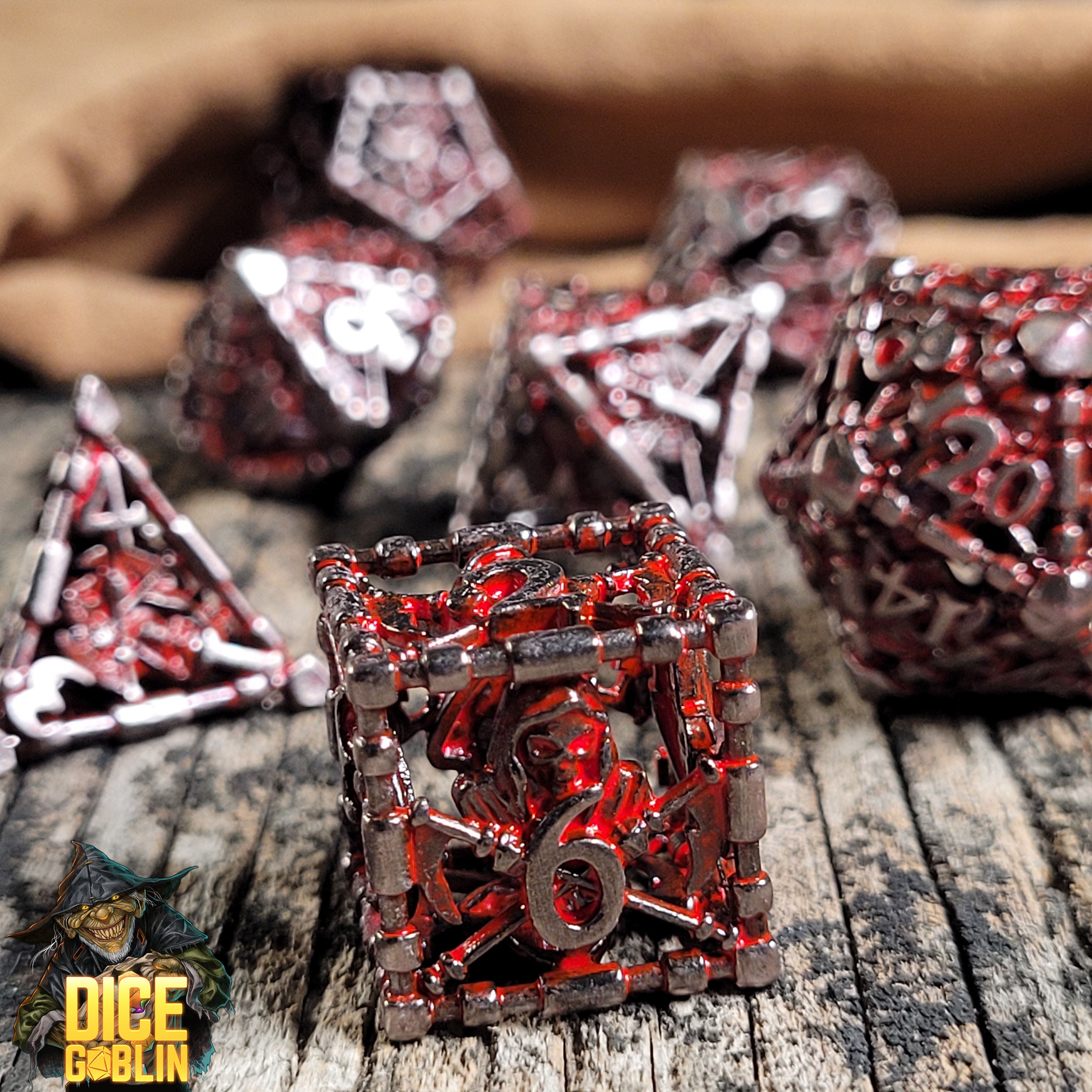 This is an environmental image of the Dice Goblin Reaper's Confine Silver with Red Wash Hollow Metal RPG Dice Set on a distressed wood surface.