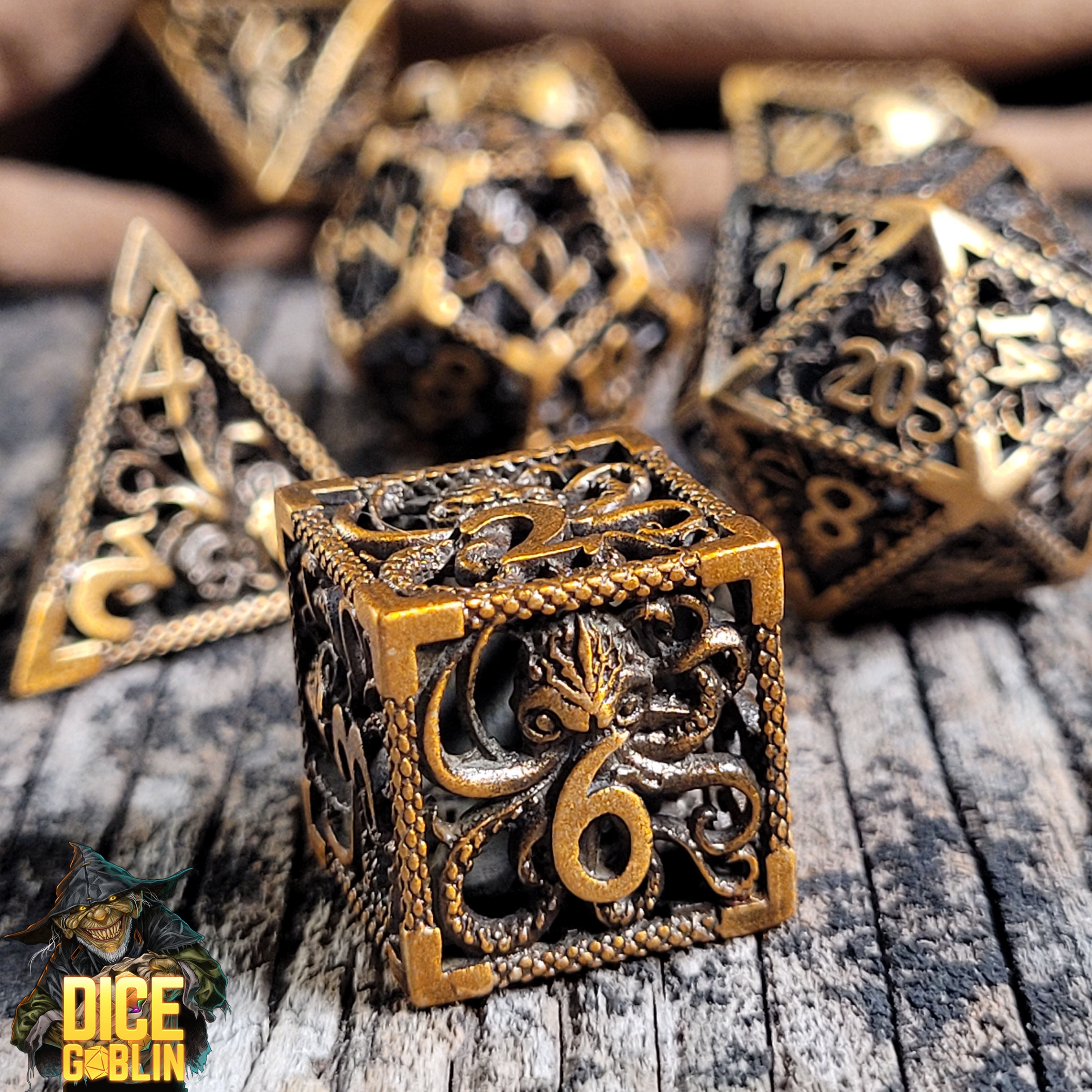This is an environmental image of the Dice Goblin Deep Dreamer Weathered Bronze Hollow Metal Dice Set on a distressed wood surface.