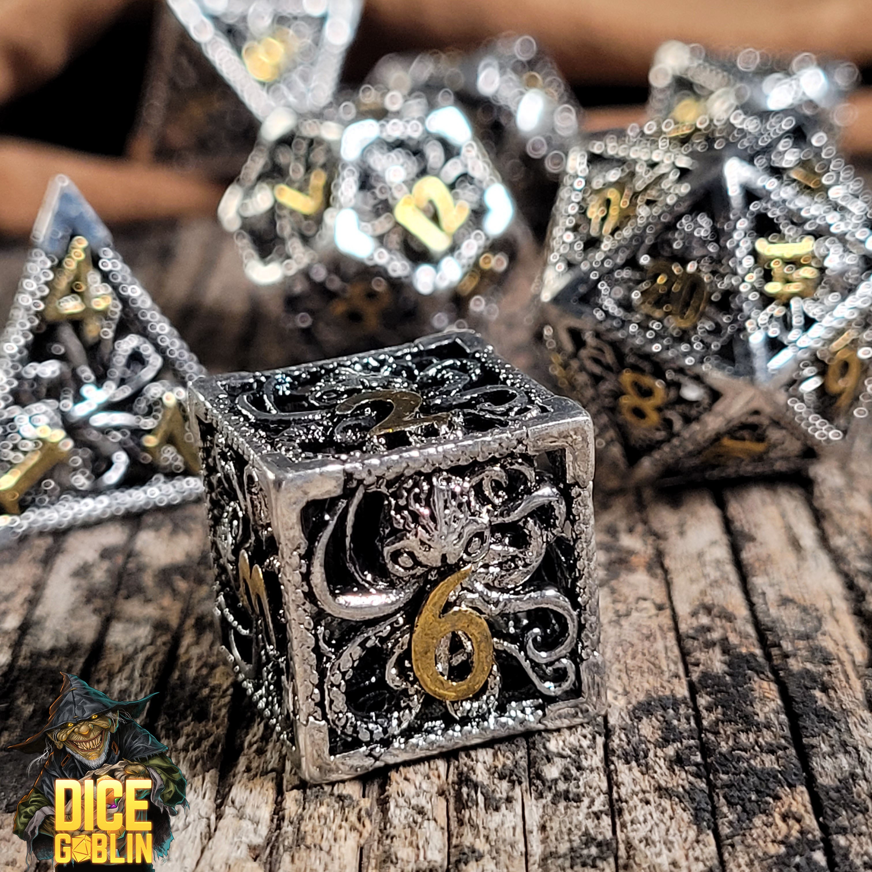 This is an environmental image of the Dice Goblin Deep Dreamer Silver Gold Hollow Metal Dice Set on a Weathered wood surface.