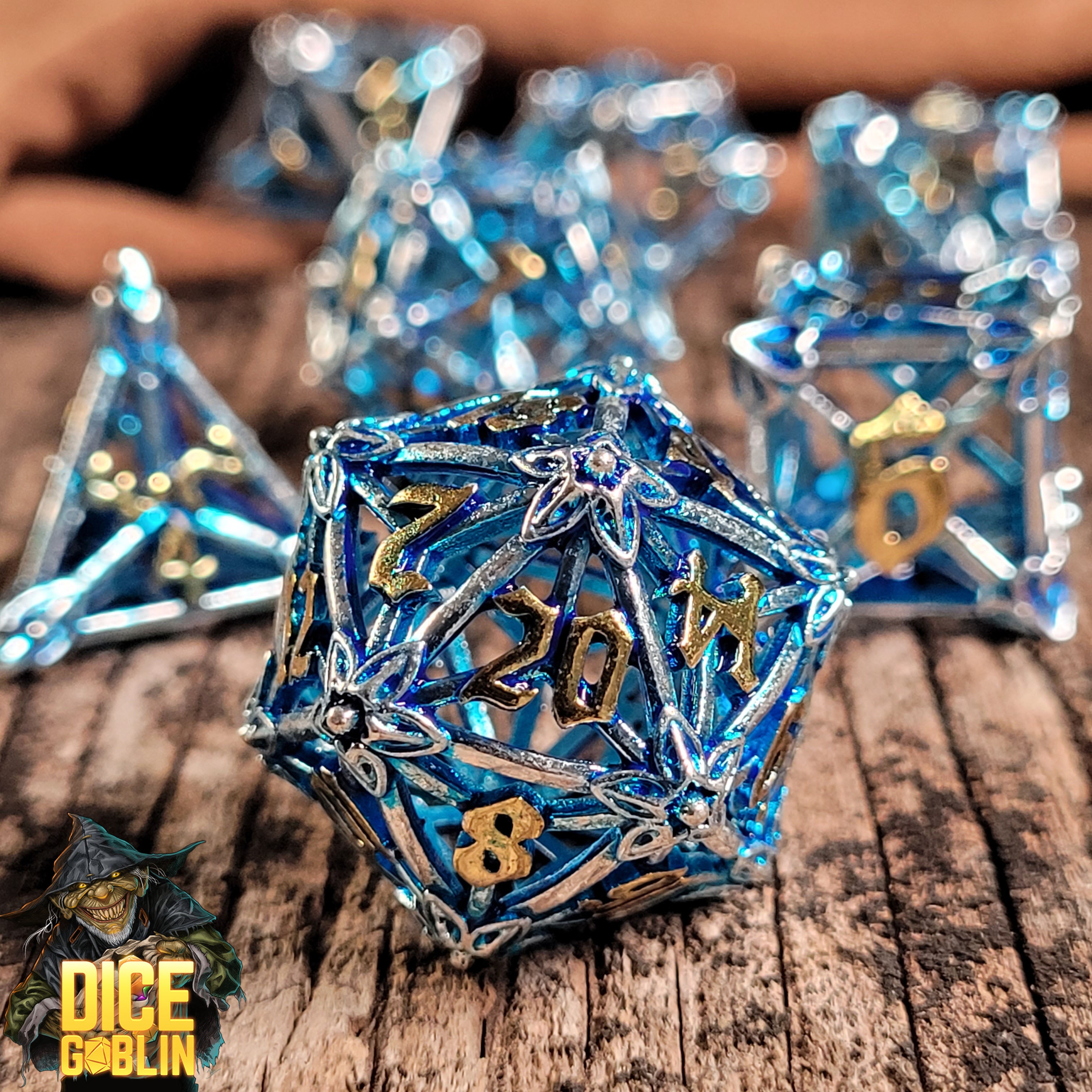 This is an environmental image of the Dice Goblin Flower Petals Silver with Blue Wash Hollow Metal RPG Dice Set on a distressed wood surface.