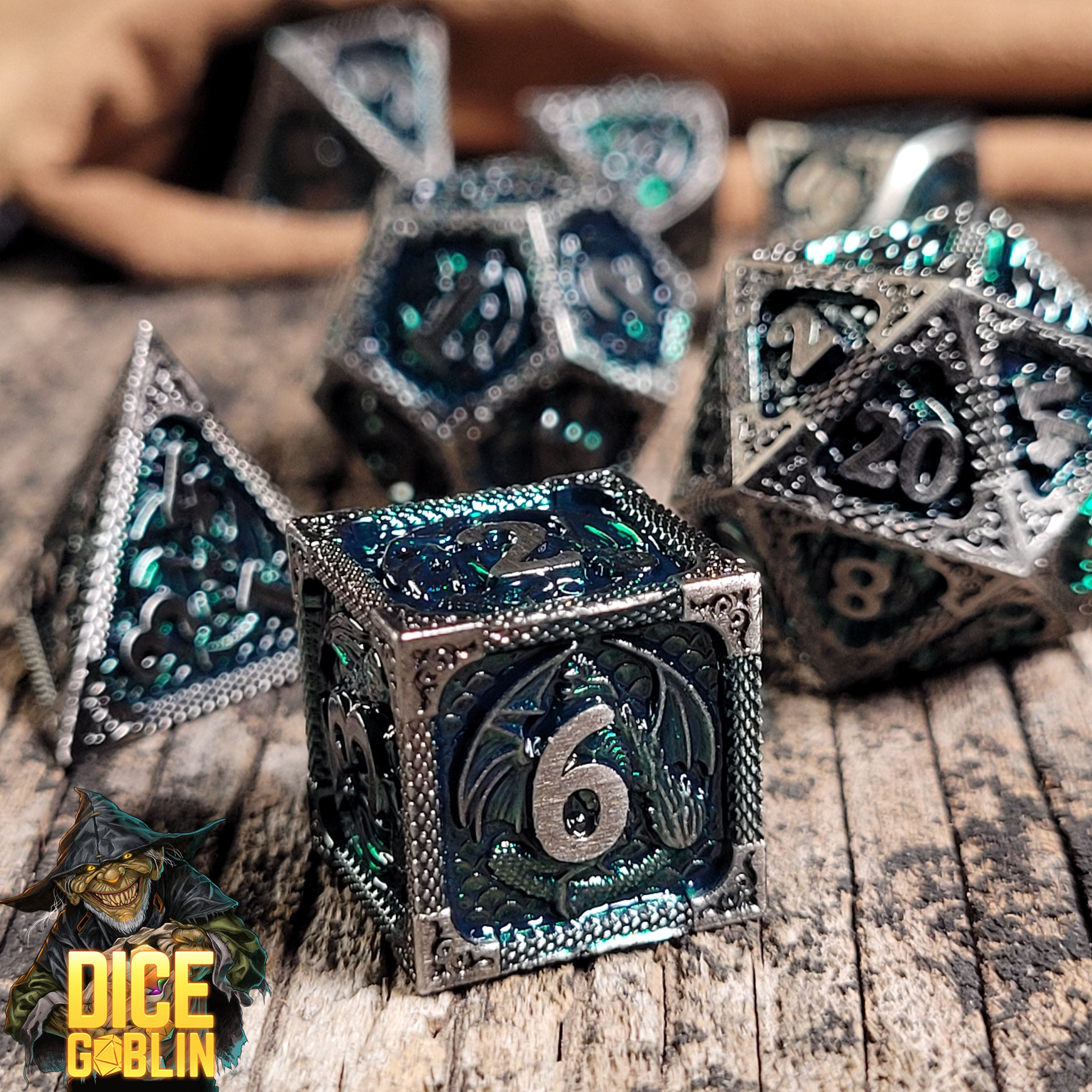This is an environmental image of the Dice Goblin Dragon's Breath Silver and Green  Metal RPG Dice Set on a distressed wood surface