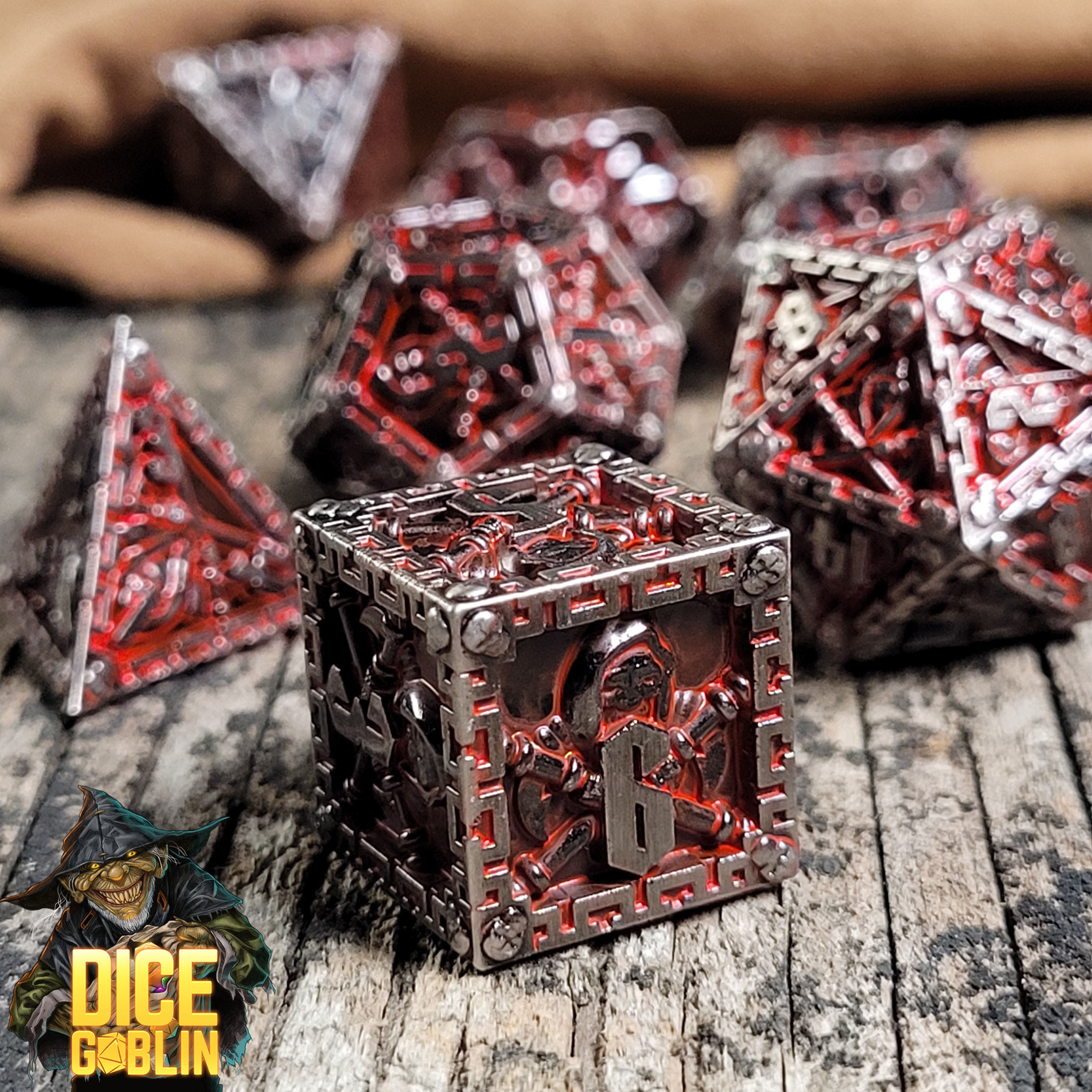 This is an environmental image of the Dice Goblin Reaper Silver with Red Wash Metal RPG Dice Set on a distressed wood surface.