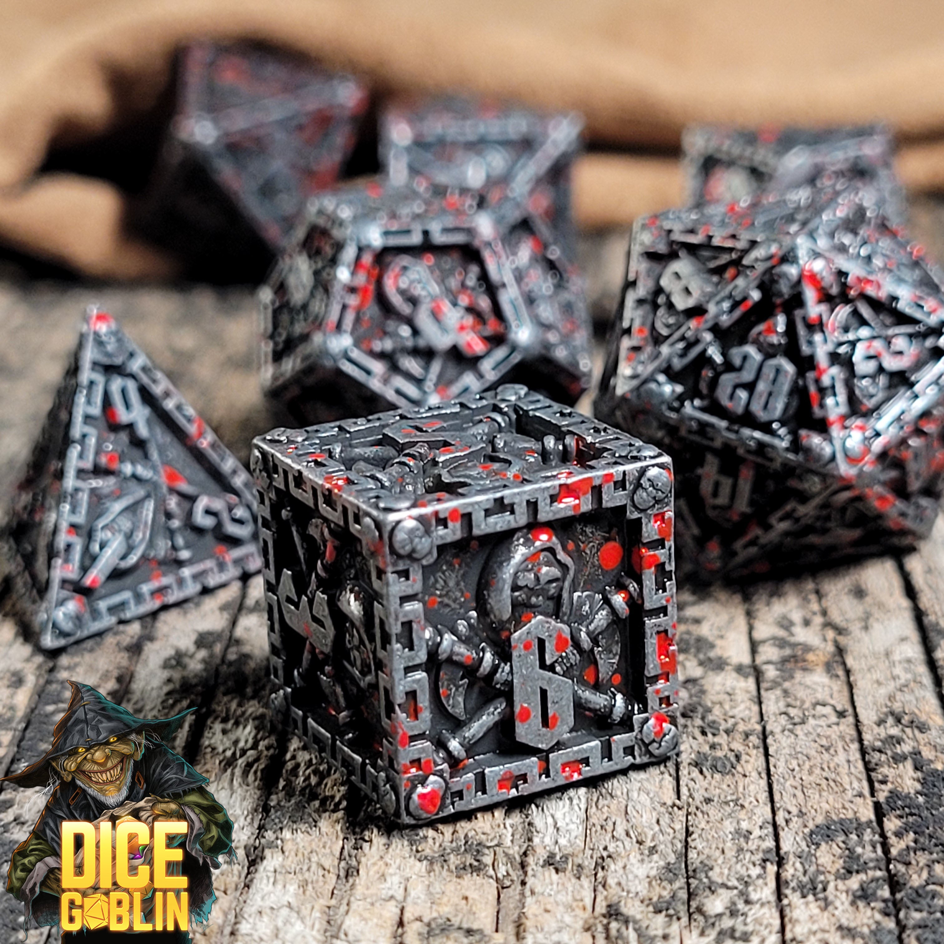This is an environmental image of the Dice Goblin Reaper Weathered Silver with Blood Splatter Metal RPG Dice Set on a distressed wood surface.