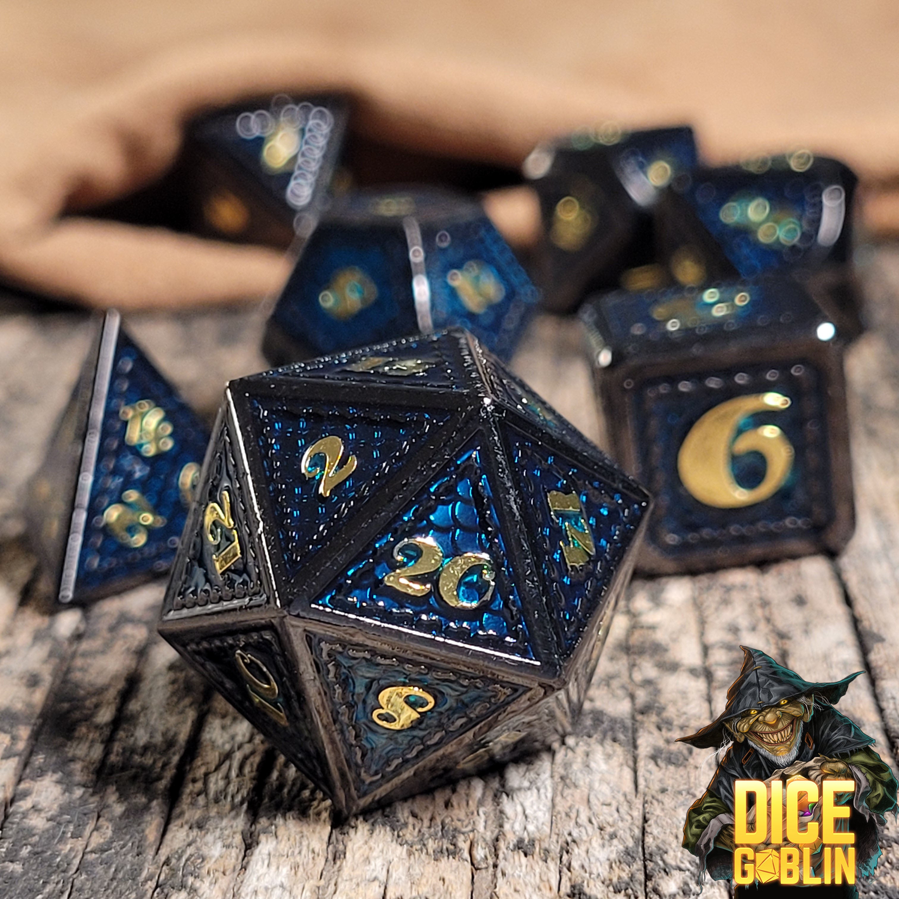 This is an environmental image of the Dice Goblin Gunmetal and Metallic Blue Metal RPG Dice Set on a distressed wood surface.