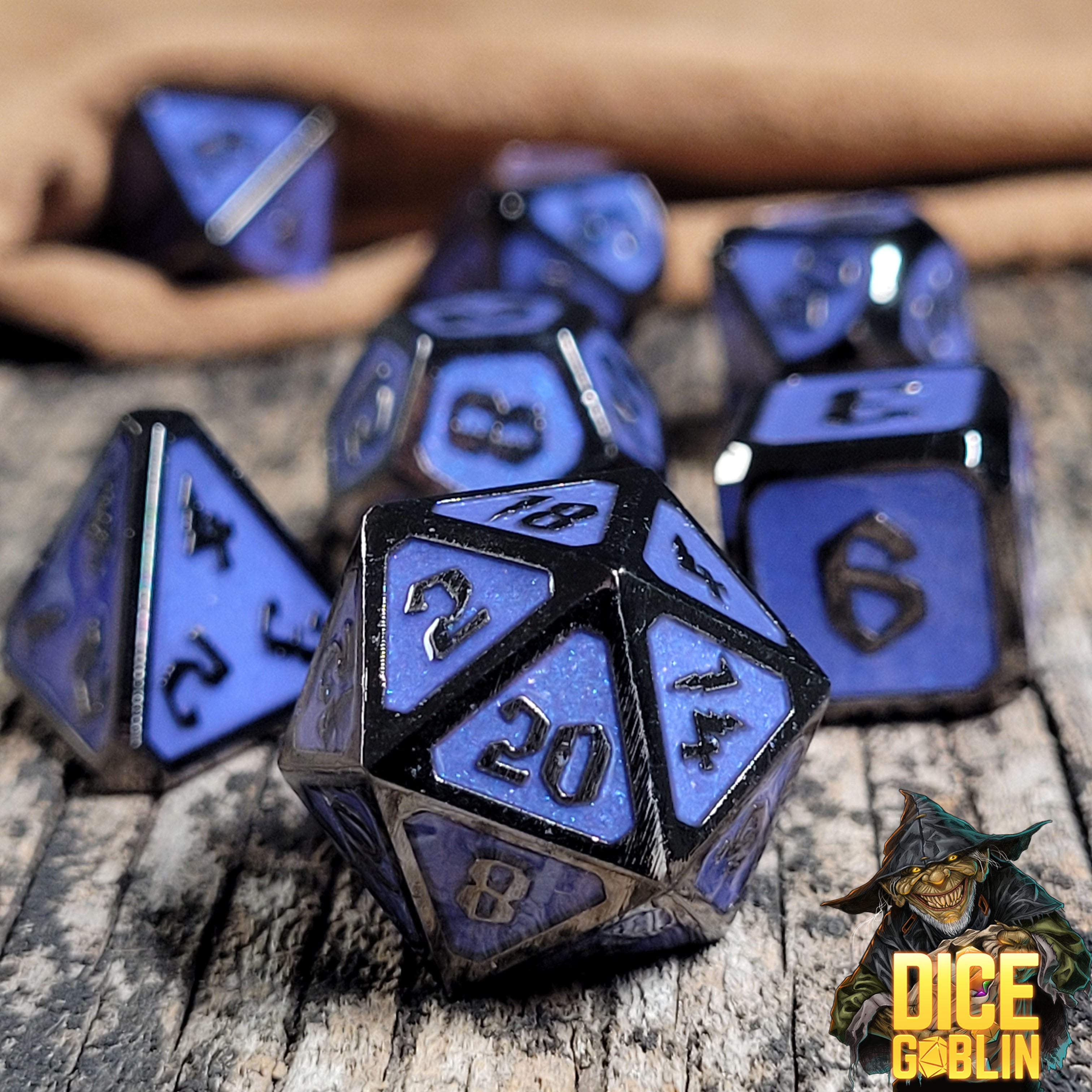 This is an environmental image of the Dice Goblin Framed Black with Blue Glitter Metal RPG Dice Set on a distressed wood surface.