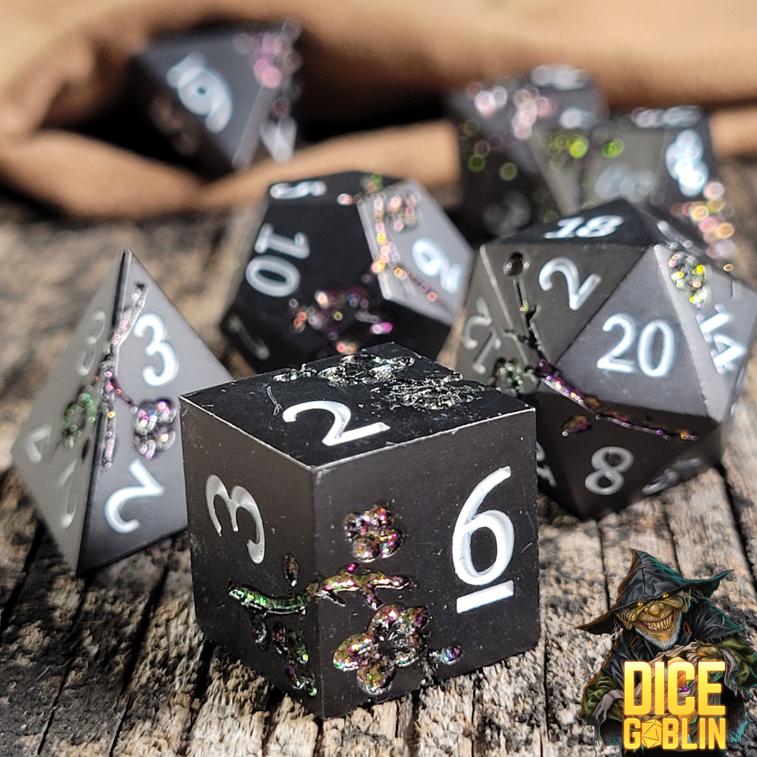 This is an environmental image of the Dice Goblin Flowers Black with Glitter Metal RPG Dice Set on a distressed wood surface.