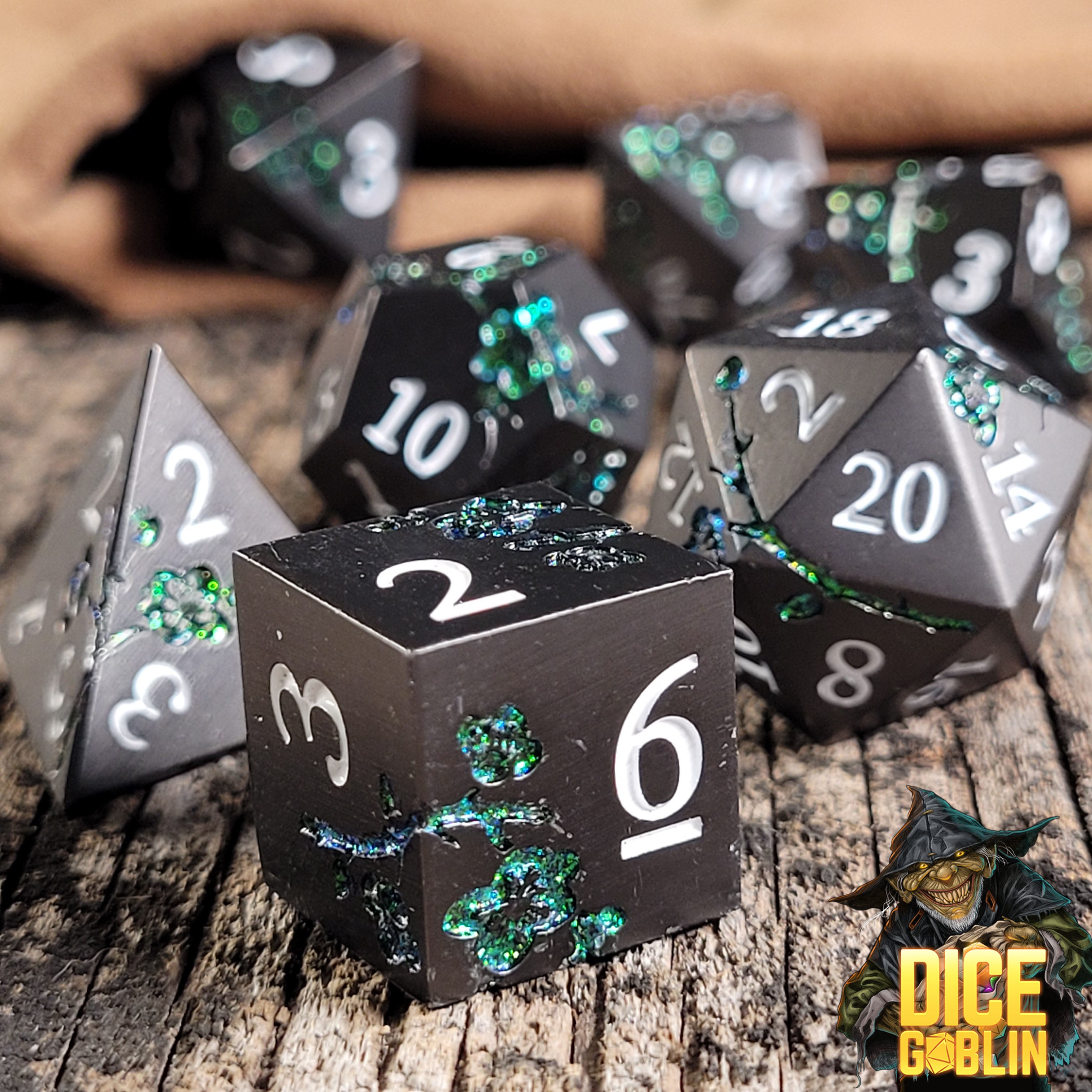This is an environmental image of the Dice Goblin Flowers Black with Green Glitter Metal RPG Dice Set on a distressed wood surface.