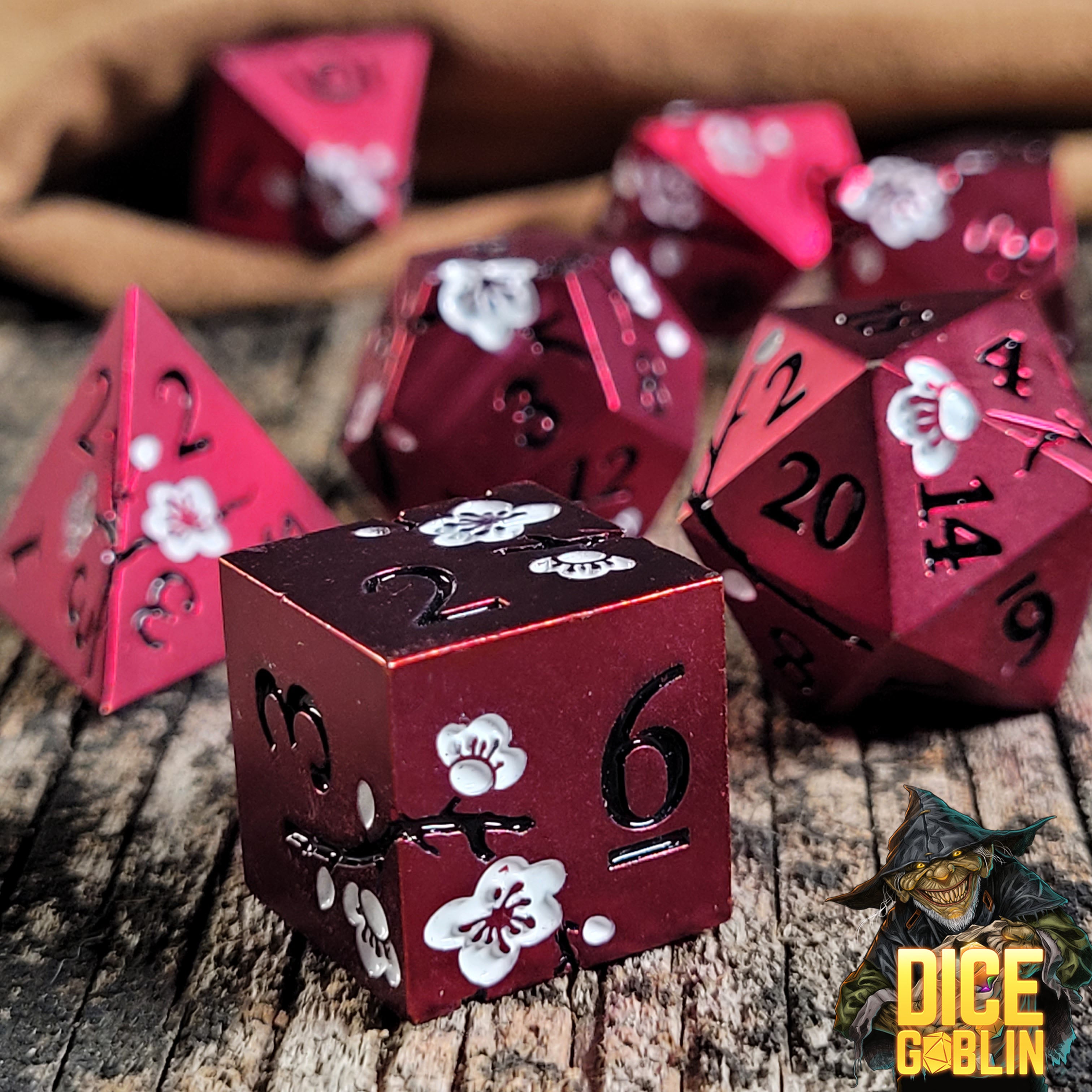 This is an environmental image of the Dice Goblin Flowers Red with White Metal RPG Dice Set on a distressed wood surface.