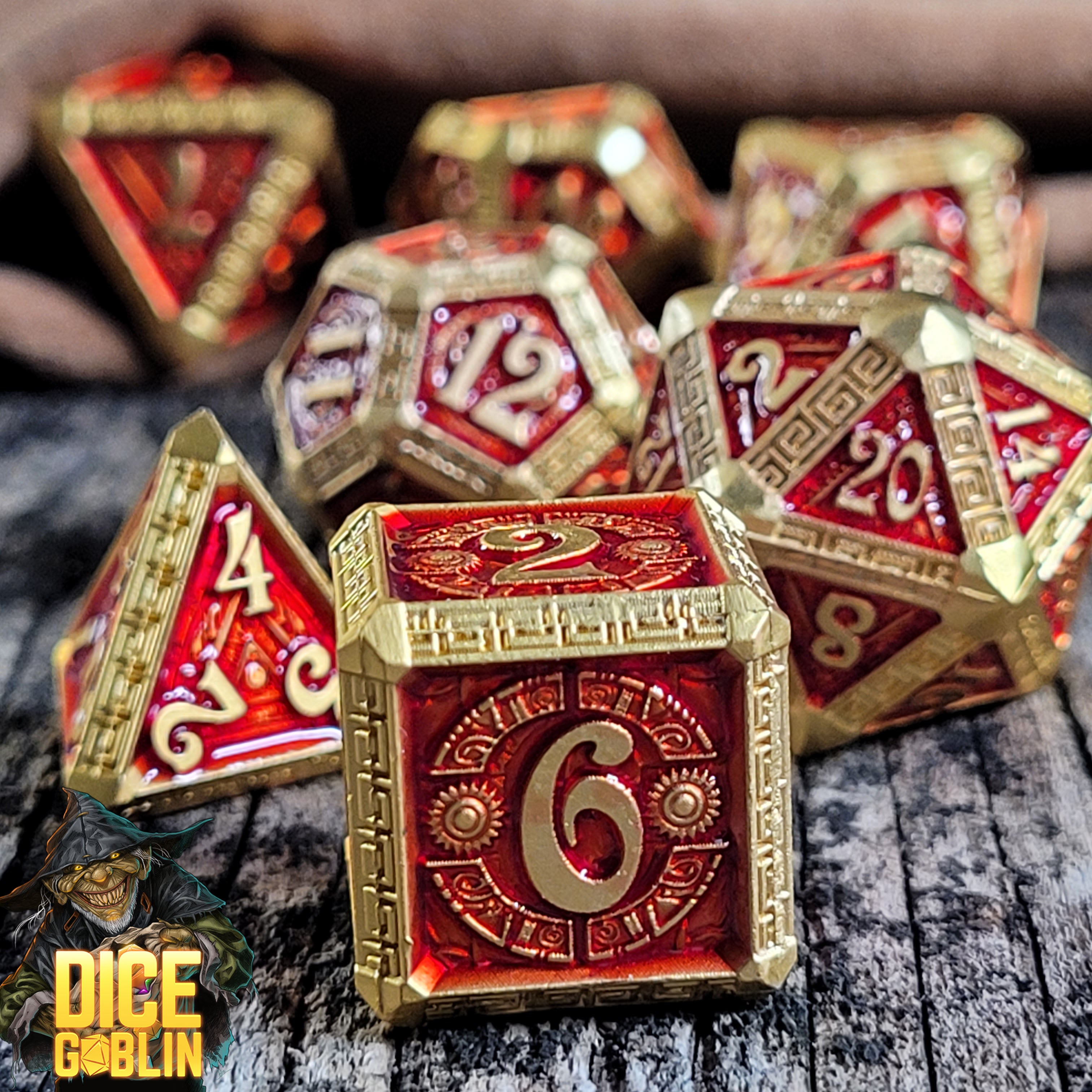 This is an environmental image of the Dice Goblin Greek Key Gold Red Metal RPG Dice Set on a distressed wood surface.