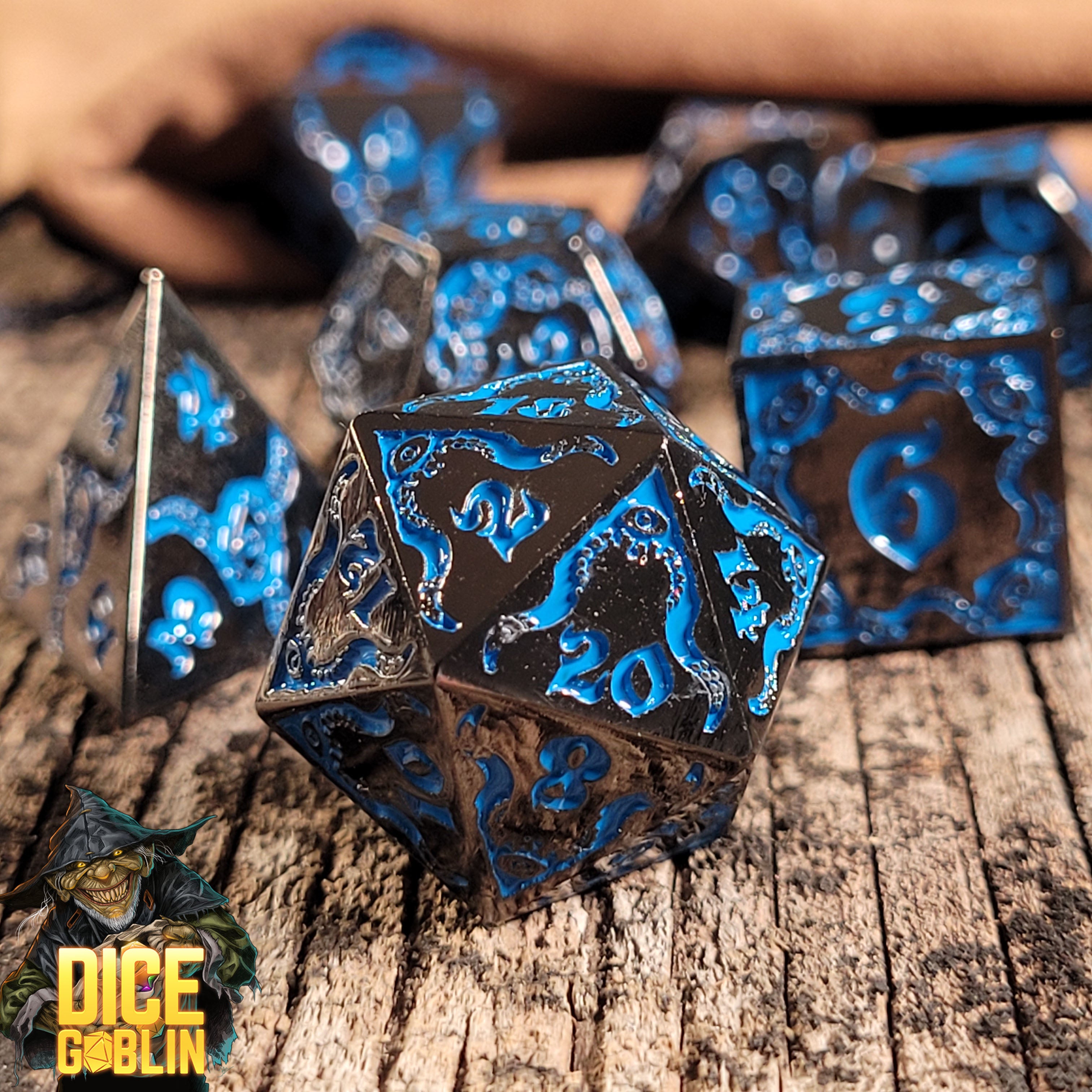 This is an environmental image of the Dice Goblin Devouring Mystery Black with Blue Metal RPG Dice Set on a distressed wood surface.