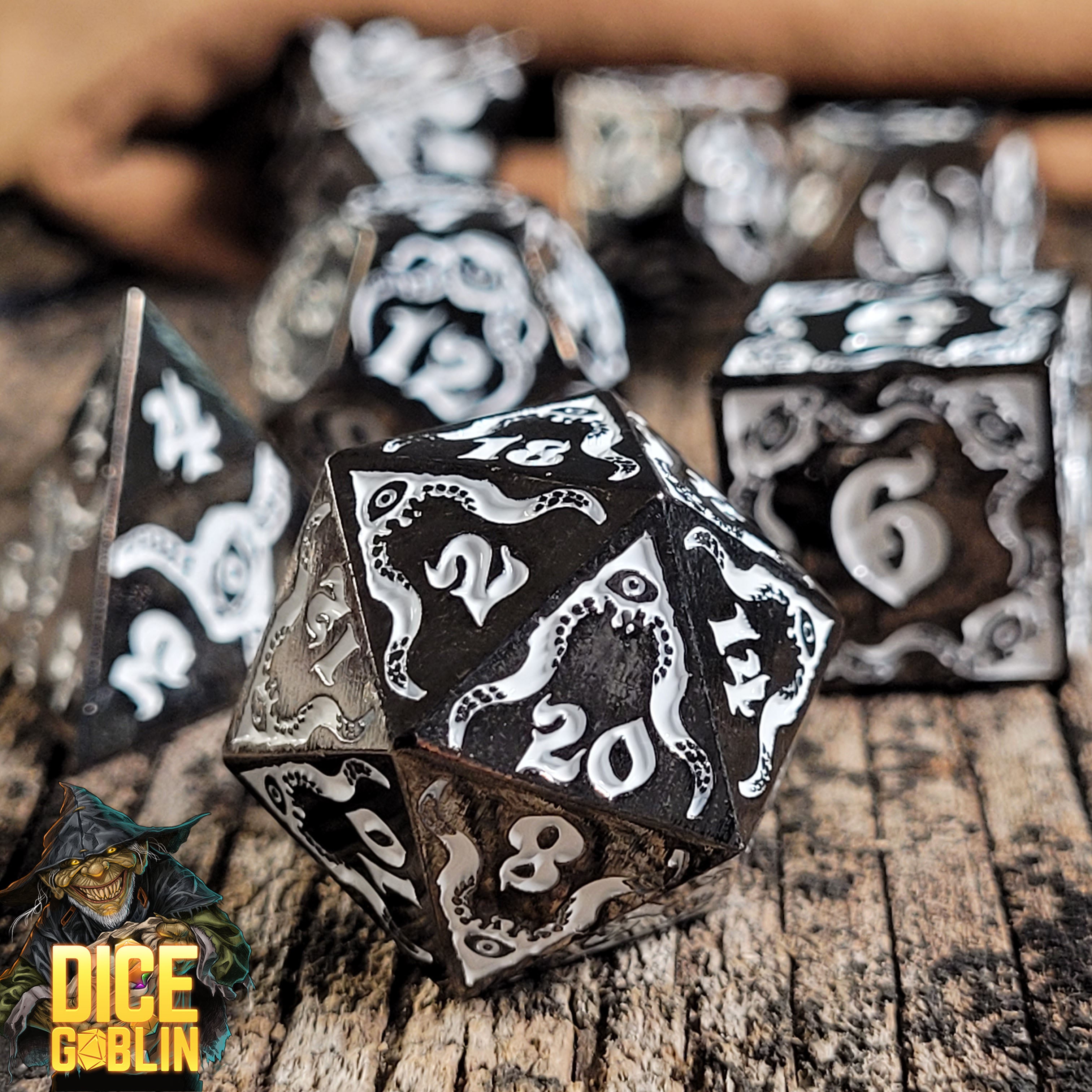 This is an environmental image of the Dice Goblin Devouring Mystery Black with White Metal RPG Dice Set on a distressed wood surface.
