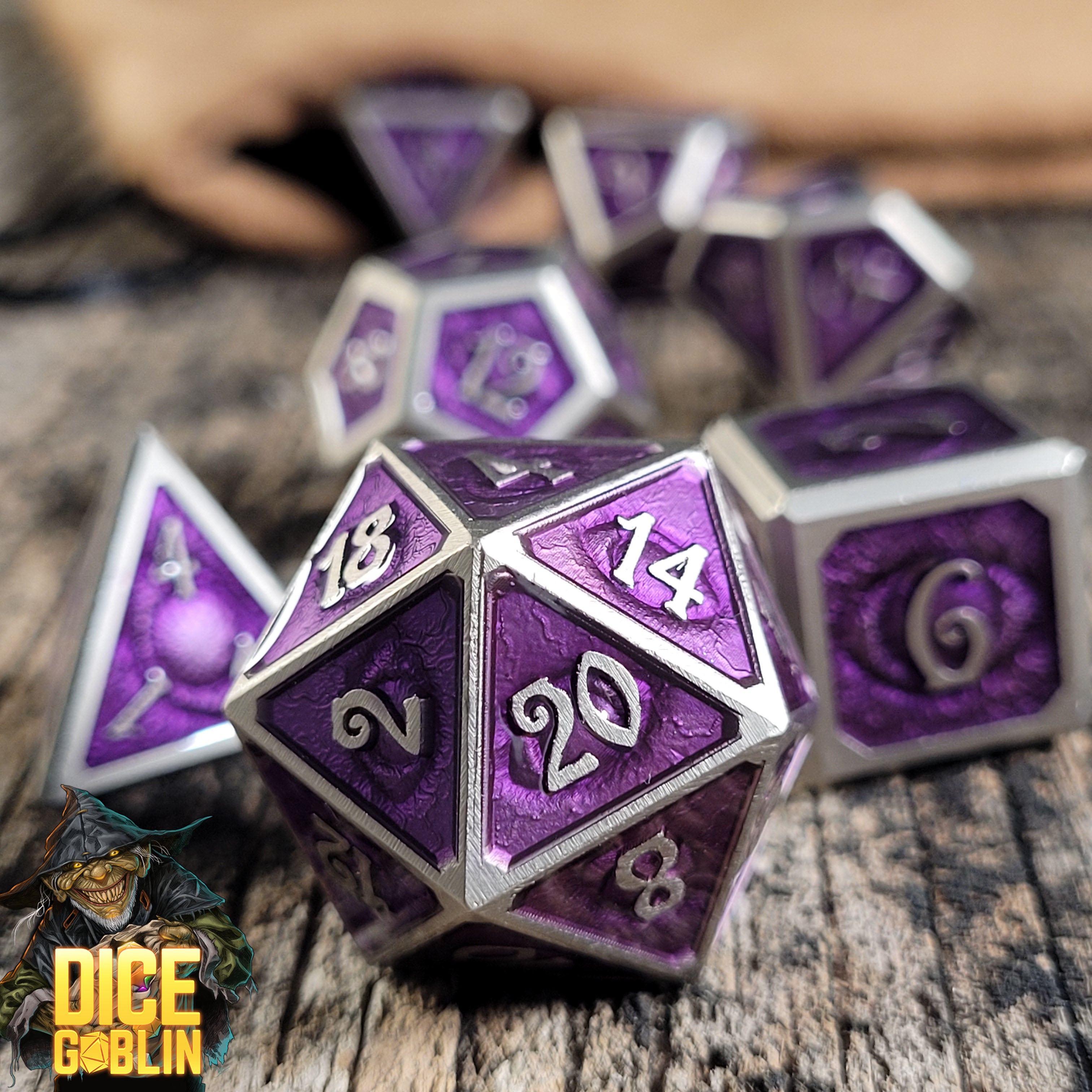 This is an environmental image of the Dice Goblin Eyes Silver with Foiled Purple Metal RPG Dice Set on a distressed wood surface.