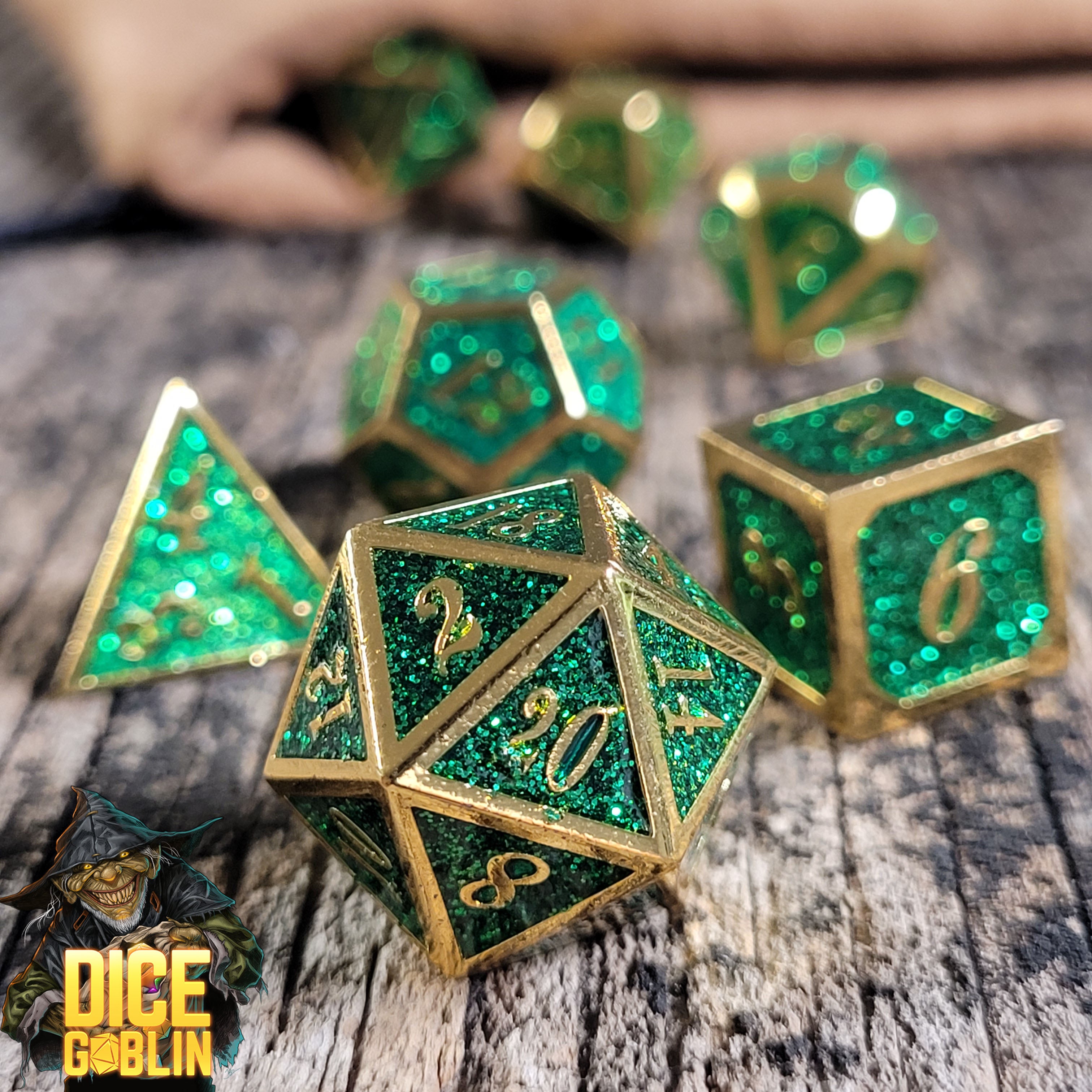 This is an environmental image of the Dice Goblin Framed Gold with Green Glitter Metal RPG Dice Set on a distressed wood surface.