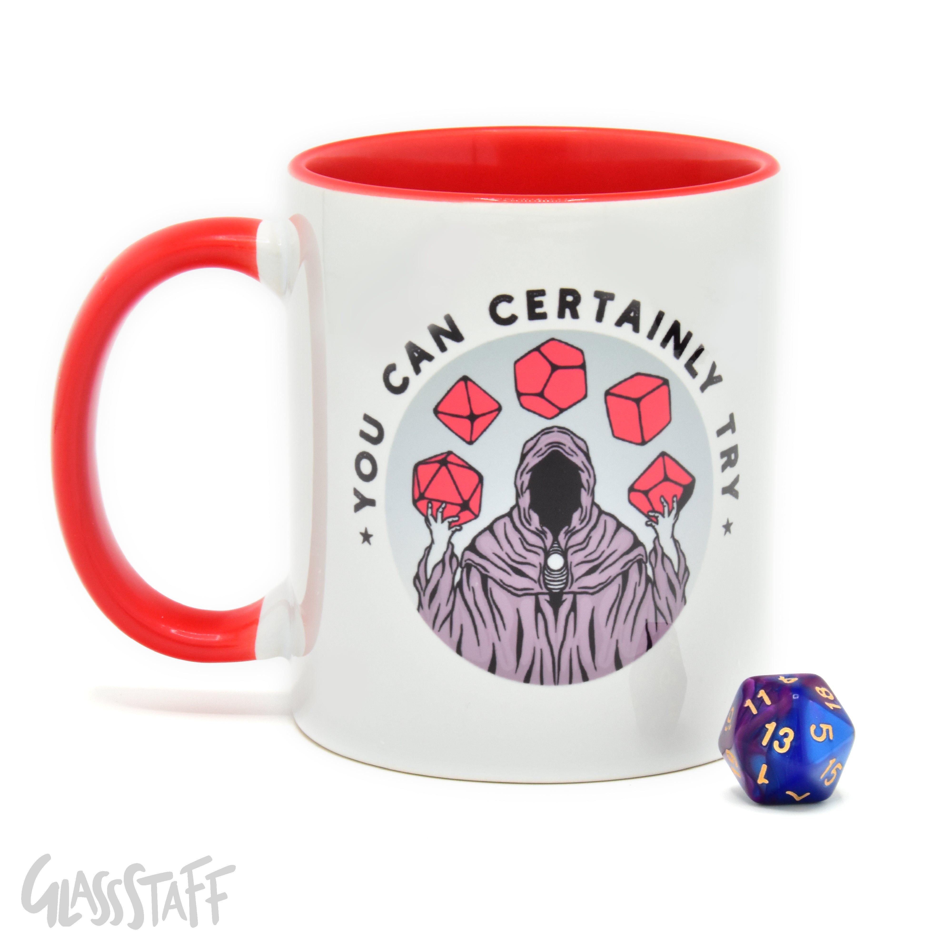 This is a white background image of the GLassStaff You Can Certainly Try ceramic mug. It shows the white mug with a red handle, red inside, and You Can Certainly Try design. It also shows the D20 die included with the mug.